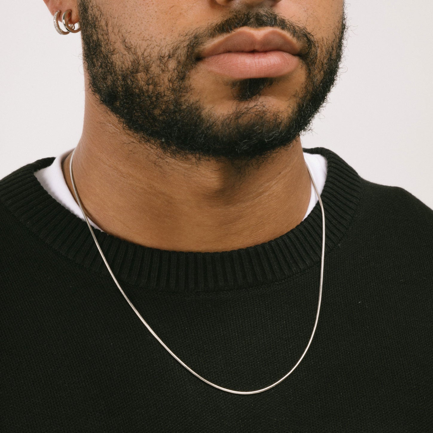 A model wearing the 1.5mm Snake Chain is made of durable stainless steel, measuring 22 inches in length. It's also non-tarnish and water-resistant for extra protection.
