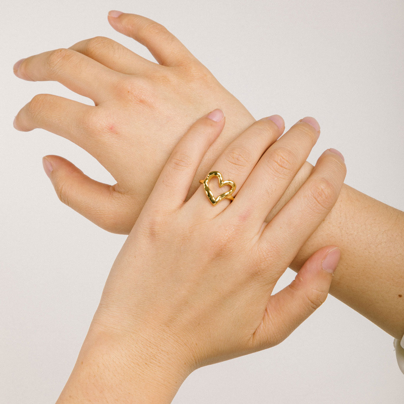 A model wearing the Ai Heart Ring in Gold is crafted with of 14K Gold Plated Stainless Steel, ensuring a durable and non-tarnishing construction. This piece is also water resistant and made without Lead, Nickel, or Cadmium for added safety. This is a single ring, with no ability to adjust.