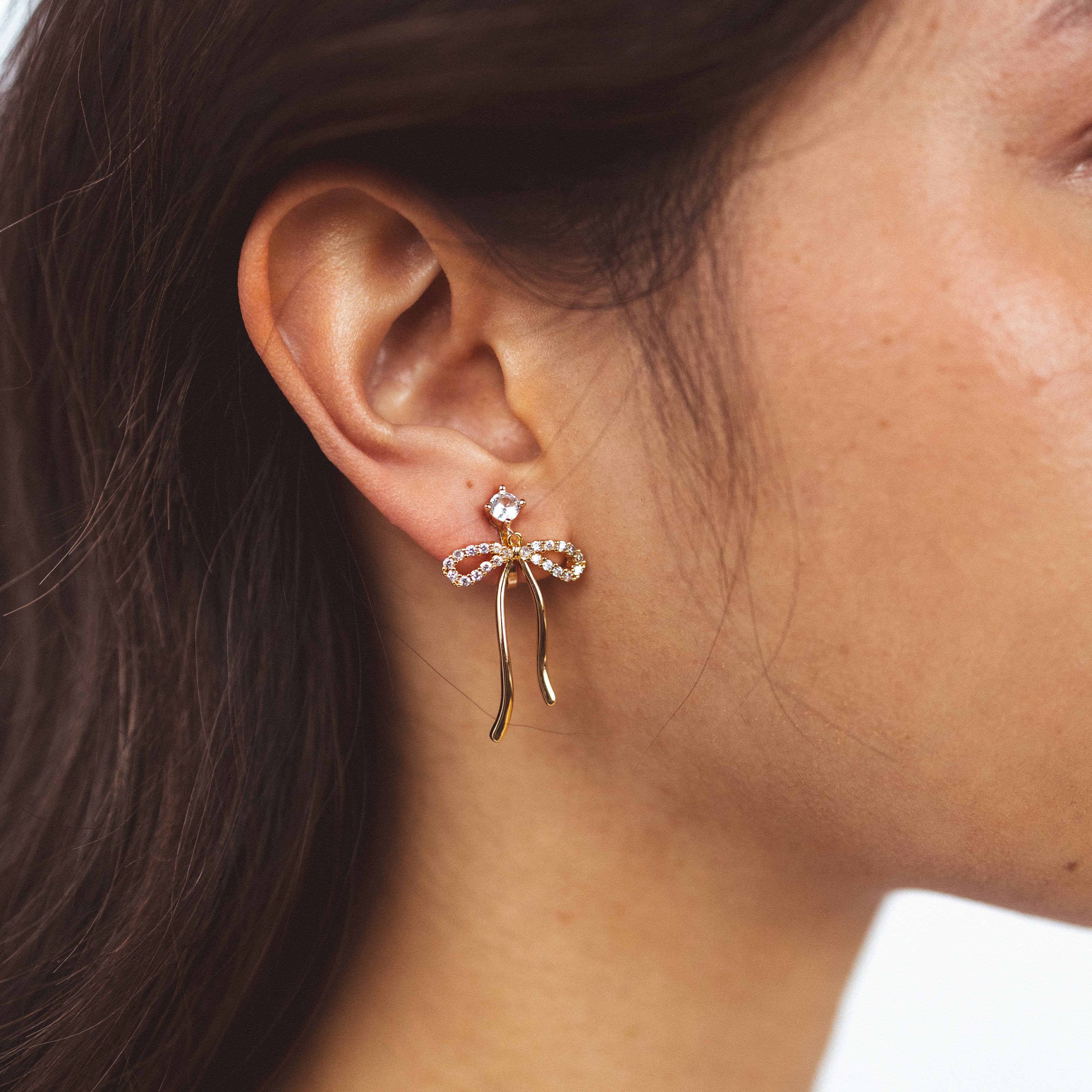 A model wearing the Anna Clip On Earrings, offer an adjustable fit and 24-hour hold for unrivaled comfort. Elevate your style effortlessly with the touch of elegance these earrings provide.