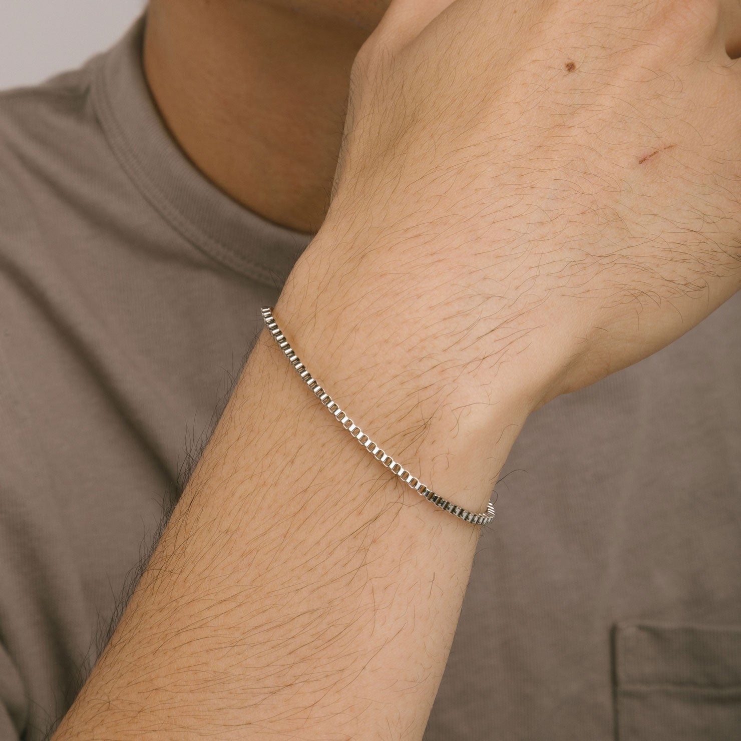 A model wearing the Box Chain Bracelet in Silver is Stainless Steel, offering a non-tarnish, water-resistant finish.