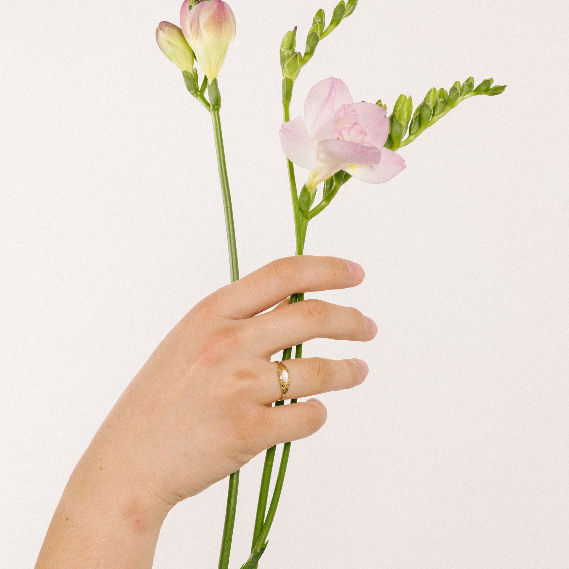 A model wearing the Celestial Ring, adorned with a luminous Mother of Pearl centerpiece and 18K Gold Plated Stainless Steel. A singularly exquisite piece, sure to never fade nor tarnish, and resilient to water.