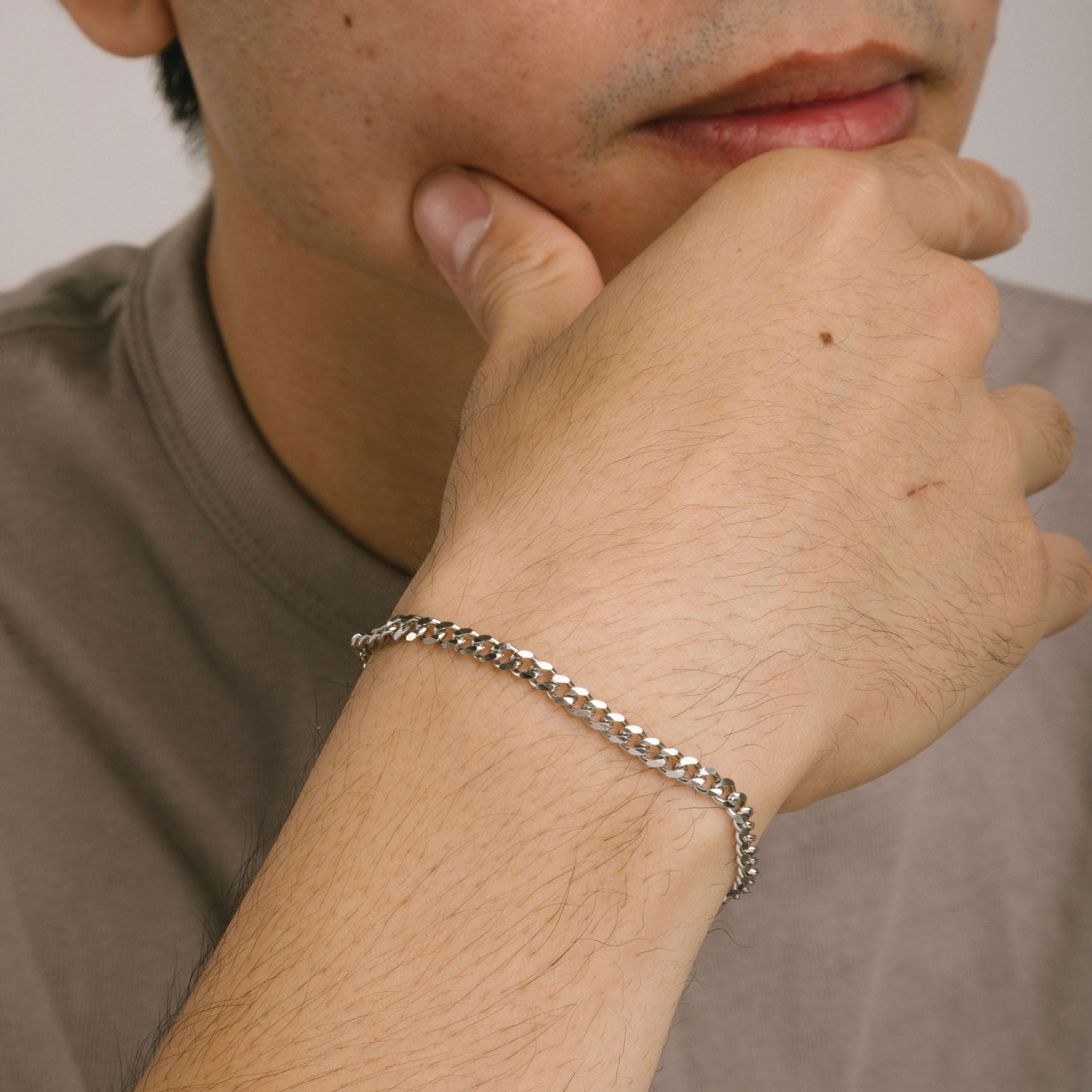 A model wearing the Cuban Chain Bracelet is made of durable stainless steel, and offers a non-tarnish finish and water resistance.