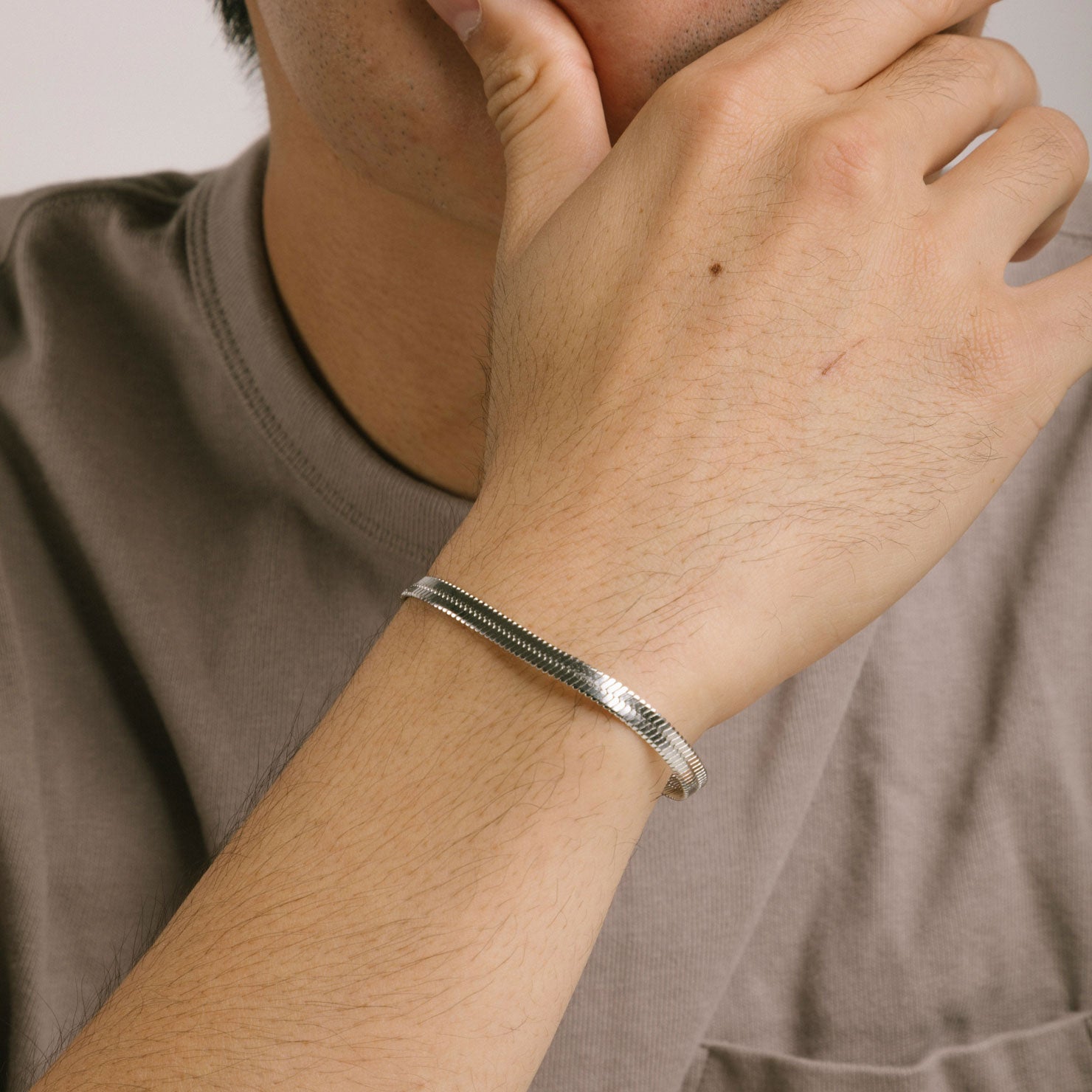 A model wearing the Herringbone Chain Bracelet in Silver is crafted with stainless steel and measures 18cm long and 5mm wide. It is also non-tarnish and water resistant.