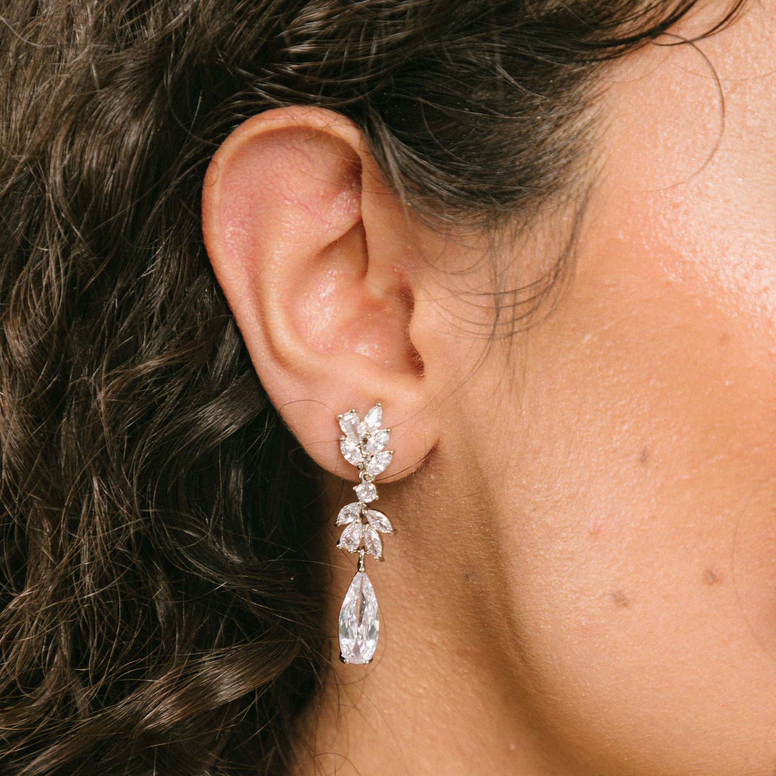 A model wearing the Lobelia Clip-On Earrings feature a secure, comfortable hold that lasts for 8-12 hours. Attached to silver-plated metal alloy, these earrings are fitted with foam padding for optimal comfort and ease-of-use. Ideal for all ear types, from thin/small to thick/large, along with sensitive ears and those in the healing/stretching process. Cubic Zirconia adds a hint of sparkle. Please note, item includes one pair of earrings.