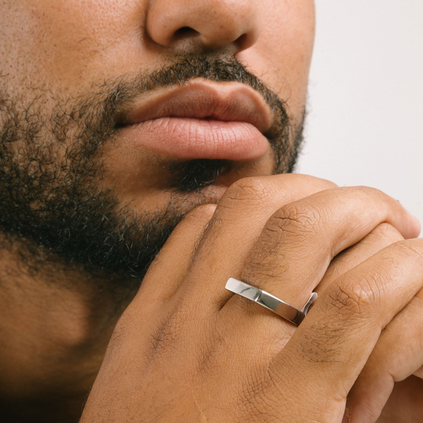 A model wearing the Straight Band Ring in Silver crafted from Stainless Steel, measuring 4mm in width, and featuring non-tarnish and water-resistant properties.
