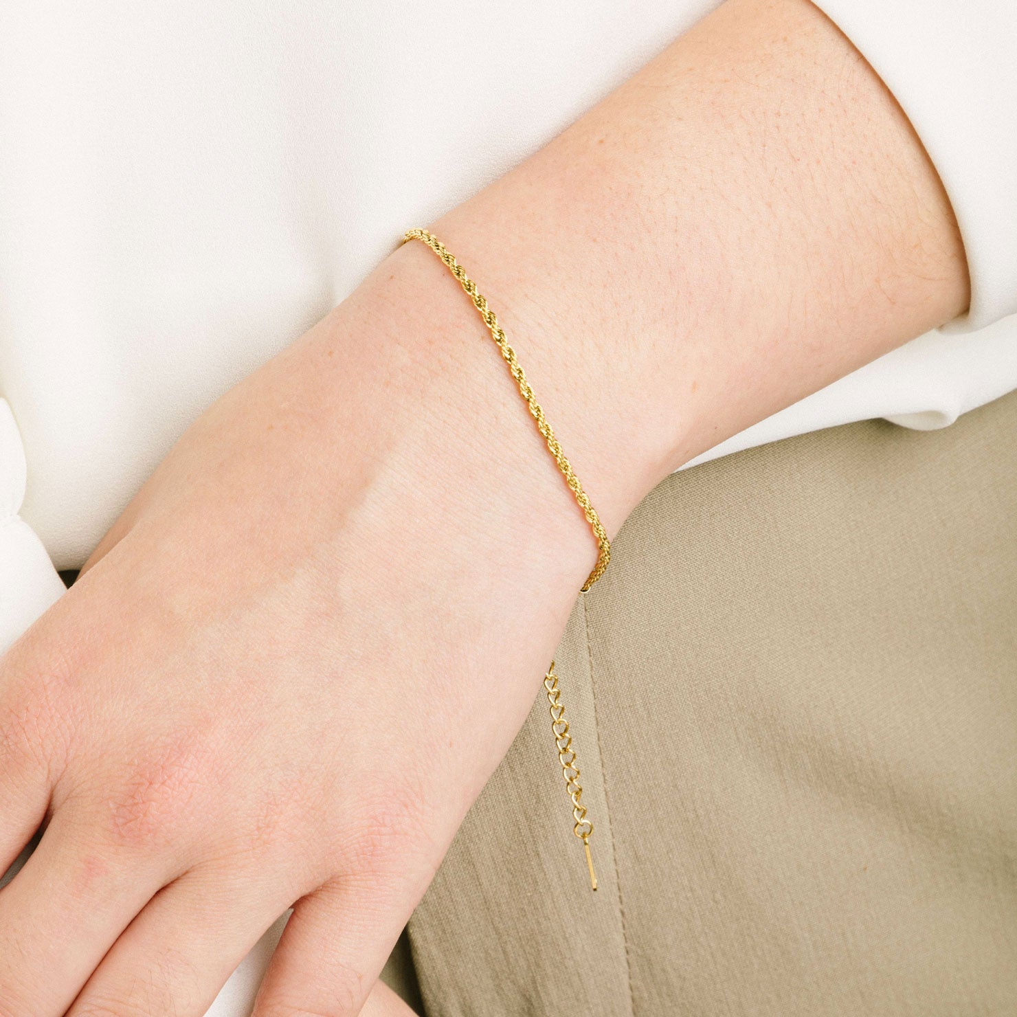 A model wearing the Twisted Chain Bracelet is crafted from 14K Gold Plated Stainless Steel, making it both non-tarnish and water resistant. It is also free from Nickel, Lead and Cadmium, ensuring a safe and durable design. Additionally, this bracelet is adjustable for a perfect fit.