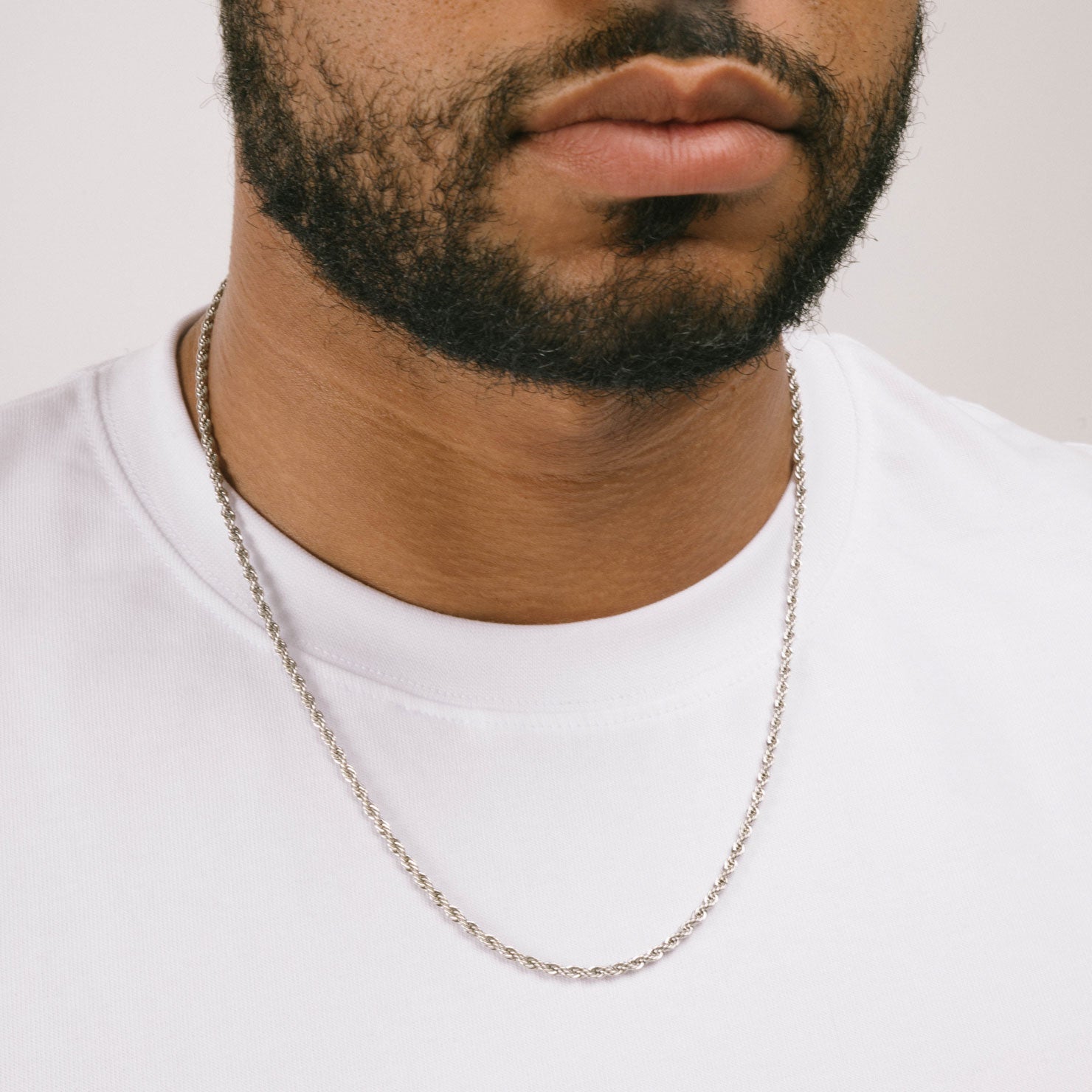 A model wearing the Twisted Rope Chain in Silver is crafted from durable stainless steel. It measures 45cm, 50cm, or 55cm in length and 3mm in width. Additionally, it is non-tarnishing, water-resistant, and safe for those with allergies.