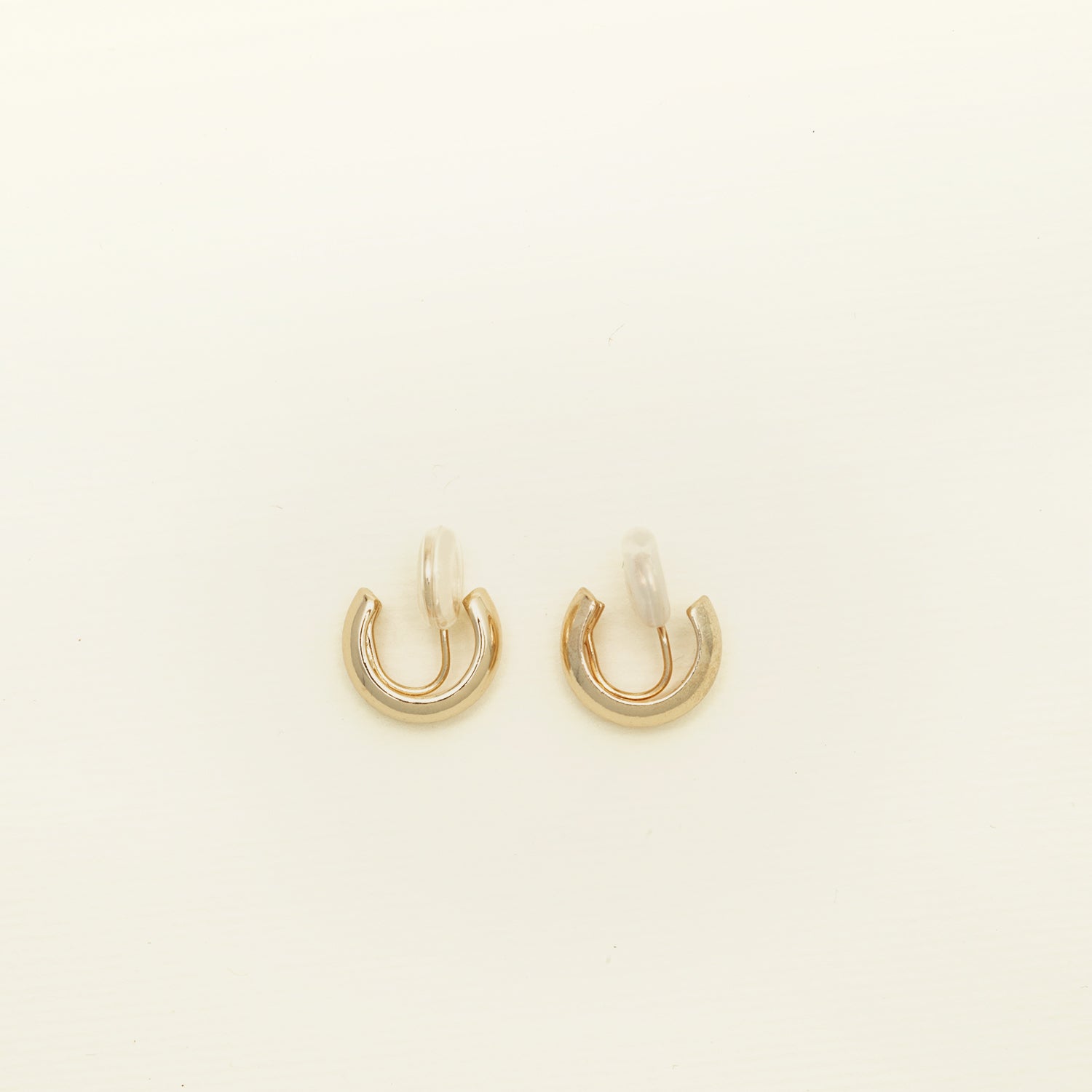Image of the Simple Gold Huggie Clip-On Earrings feature a mosquito coil closure ideal for all ear types, providing a medium-secure hold and comfortable wear for up to 24 hours. These earrings can be adjusted with a gentle squeeze of the padding forward once on the ear. Crafted with Gold tone plated copper alloy, these sophisticated earrings are also available in Silver.