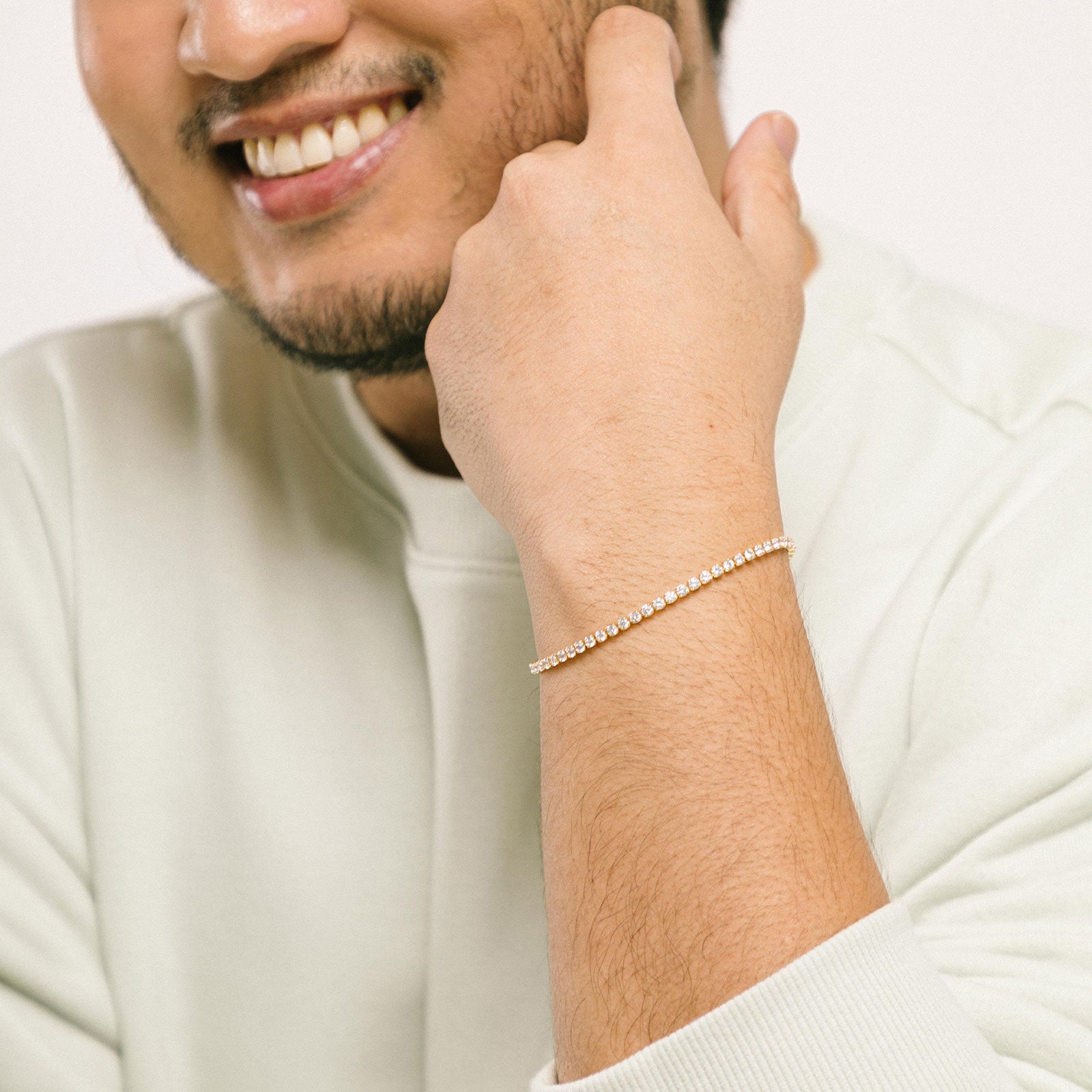 A model wearing the Tennis Bracelet is an exquisite companion to its sister piece, the Classic Tennis Necklace. Meticulously constructed from 14K gold plated metal, it is embellished with shimmering Cubic Zirconia stones. Additionally, its design is exceptionally enduring - it is tarnish-resistant, water-resistant, nickel-free, and hypoallergenic.