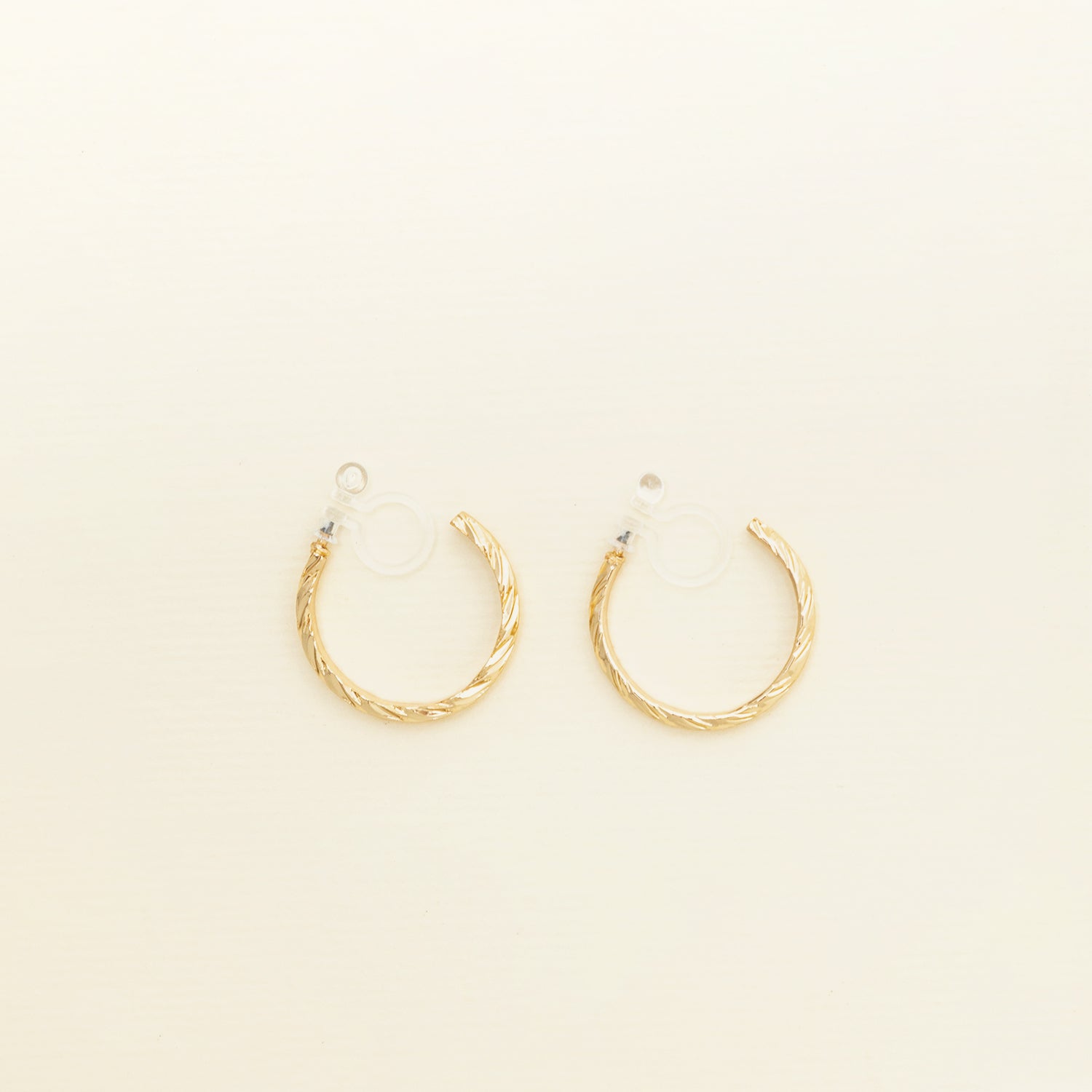 Image of the Gold Talia Hoop Clip-On Earring features a resin clip-on closure that is ideal for all ear types, providing a medium secure hold and an average comfortable wear duration of 8-12 hours. It is not adjustable, and is also available in Silver. The earrings are constructed with a gold tone metal alloy.