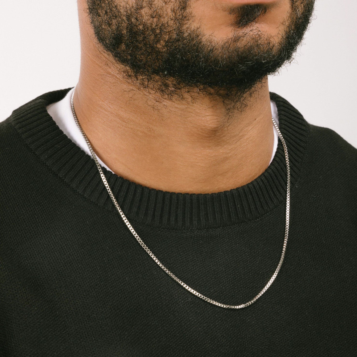 A model wearing the 2mm Square Box Chain crafted from high-grade Stainless Steel, measuring 22 inches / 56 cm in length and 2 mm in width. Weighing 5.8 grams, this chain is non-tarnishing and water-resistant.