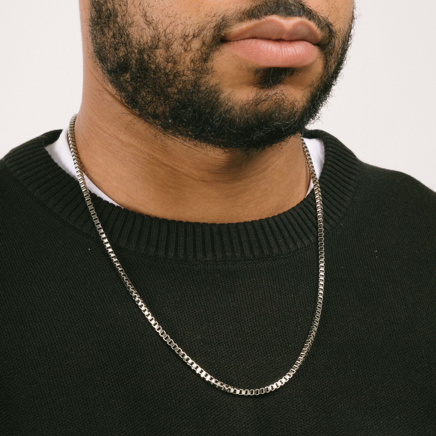 A model wearing the 3.5mm Square Box Chain crafted from high-grade Stainless Steel, measuring 22 inches / 56 cm in length and 2 mm in width. Weighing 5.8 grams, this chain is non-tarnishing and water-resistant.