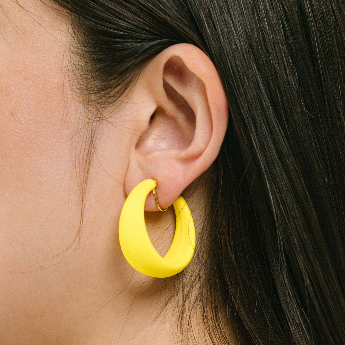 Versatile model wearing adjustable yellow clip-on hoop earrings designed for all ear types. These clip hoop earrings offer a secure hold and a comfortable wear duration of 8-12 hours. 