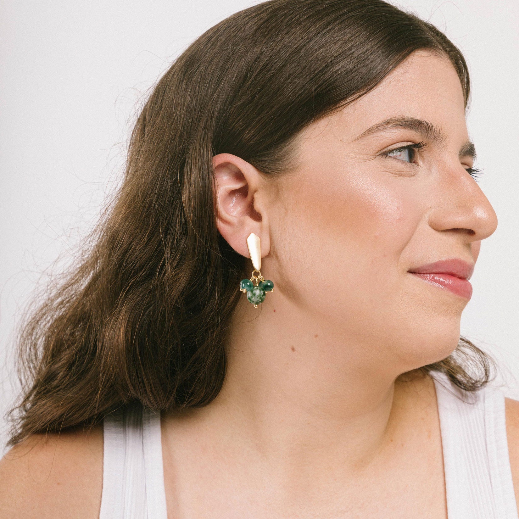 A model wear a stunning green clip-on earrings featuring agate and glass bead accents. Suitable for thick, sensitive, small, and stretched ears. Padded closure ensures a secure hold without the need for adjustments. 