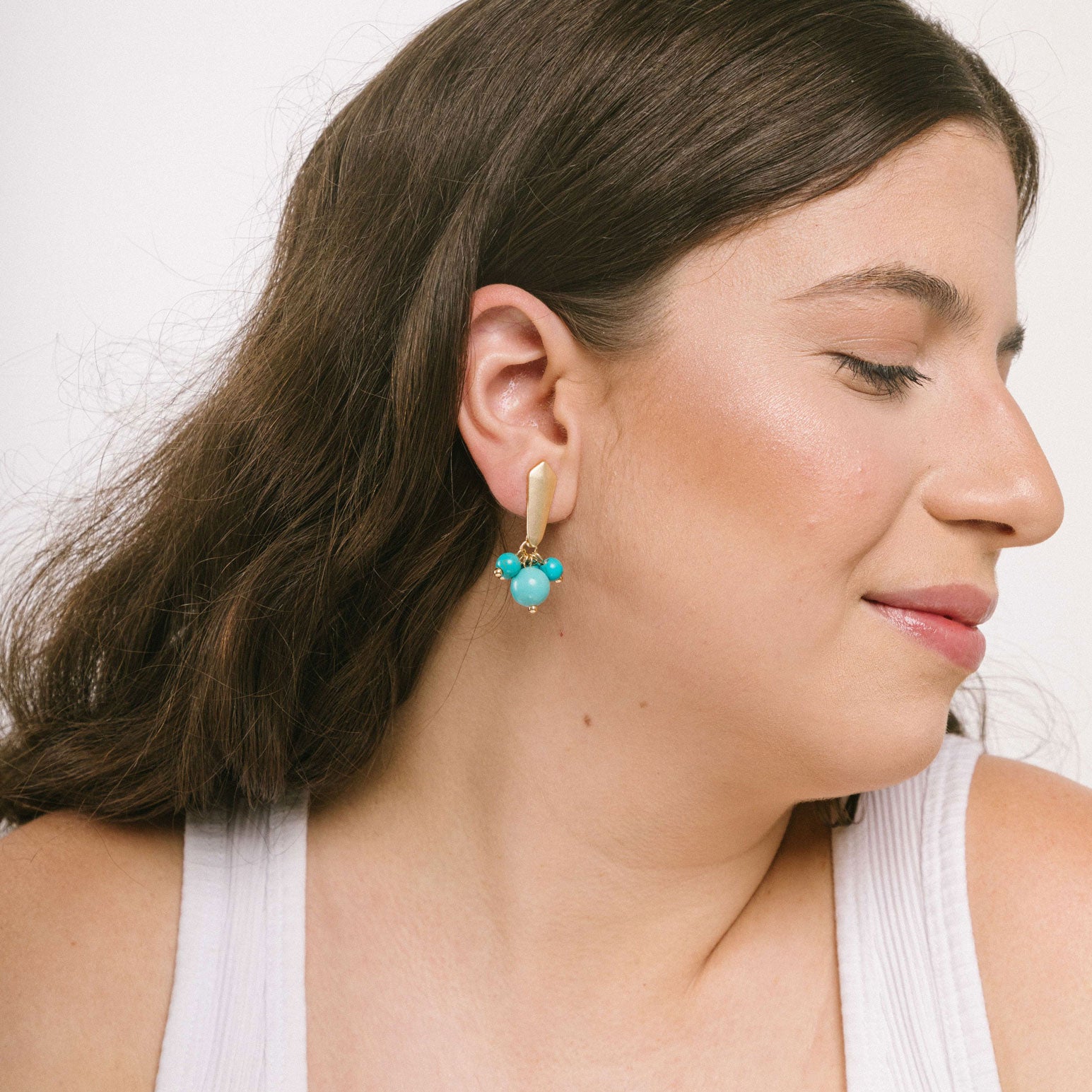 Captivating light blue clip-on earrings suitable for all ear types. These stylish earrings are made of matte gold tone copper alloy, agate, and glass bead. Secure hold with the Clip-On style and removable rubber padding.