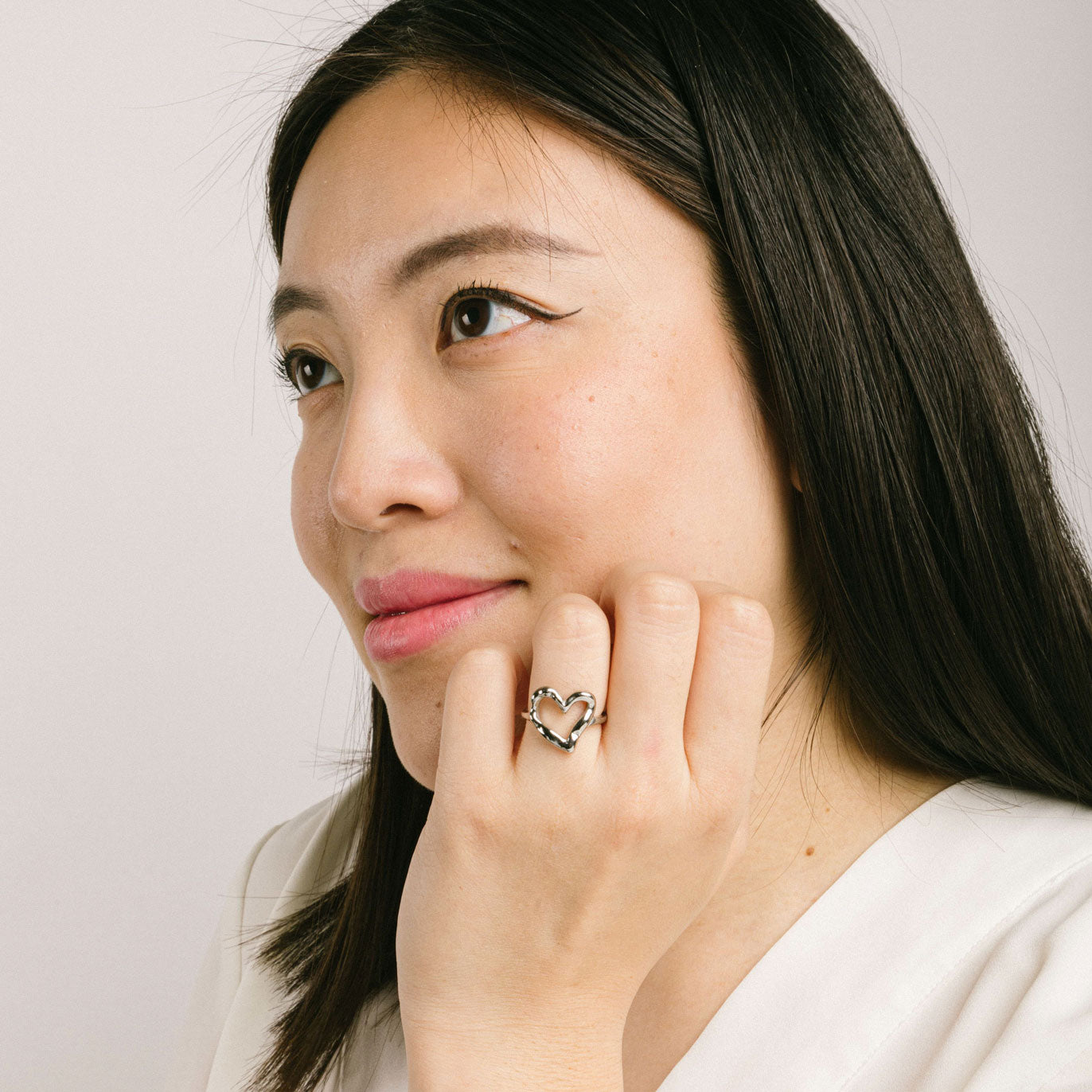 A model wearing the Ai Heart Ring in Silver is crafted with of 14K Gold Plated Stainless Steel, ensuring a durable and non-tarnishing construction. This piece is also water resistant and made without Lead, Nickel, or Cadmium for added safety. This is a single ring, with no ability to adjust.