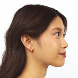 A model wearing the Alex Clip On Earrings. These versatile earrings offer a comfortable, secure 24-hour hold and adjustable fit for all ear types. Perfect for sensitive or stretched ears, they add a touch of elegance to any look.