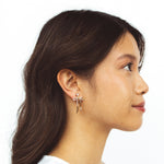 A model wearing the Anna Clip On Earrings, offer an adjustable fit and 24-hour hold for unrivaled comfort. Elevate your style effortlessly with the touch of elegance these earrings provide.