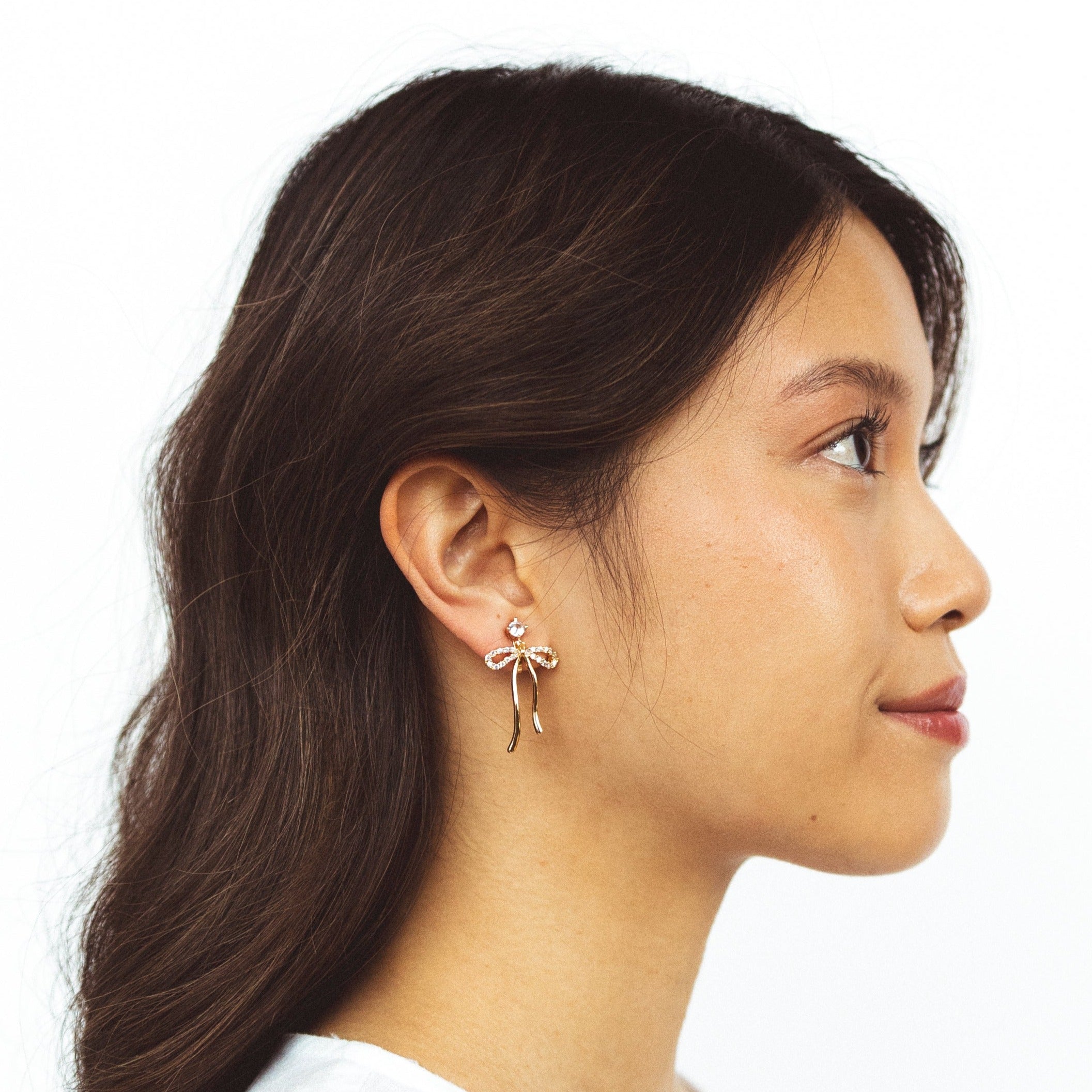A model wearing the Anna Clip On Earrings, offer an adjustable fit and 24-hour hold for unrivaled comfort. Elevate your style effortlessly with the touch of elegance these earrings provide.