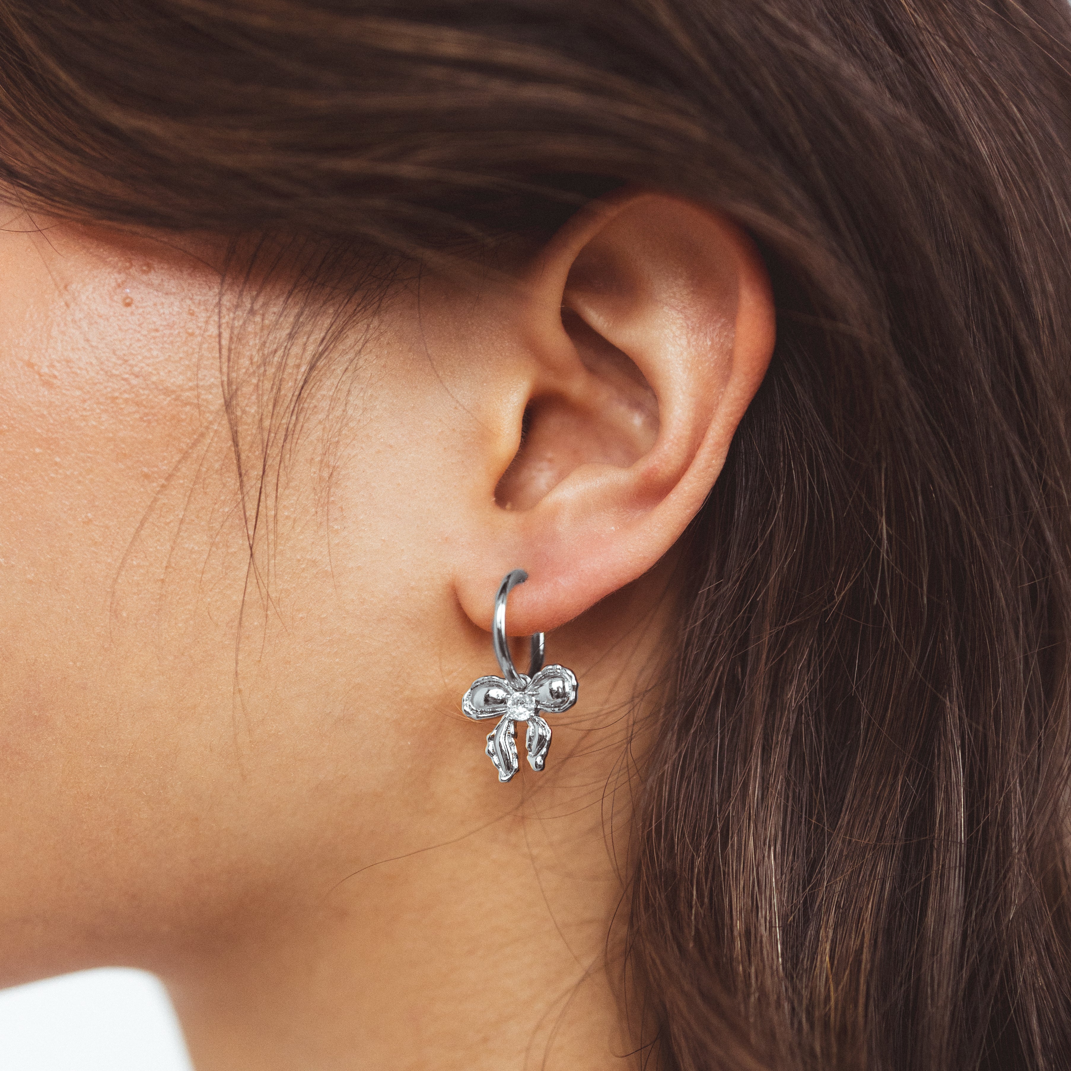 A model wearing the Ares Clip On Earrings. The sliding spring closure allows for easy adjustment to fit any ear thickness, while the gold tone copper alloy provides a secure hold. Perfect for stretched/healing ears or small/thin earlobes.