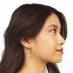A model wearing the Aurora Clip on Earrings offer versatility with a Mosquito Coil Clip-On Closure that accommodates different ear types, including Thick, Sensitive, Small, Stretched, and Keloid Prone ears. Its Medium hold strength and adjustable padding provide a comfortable fit for any occasion.