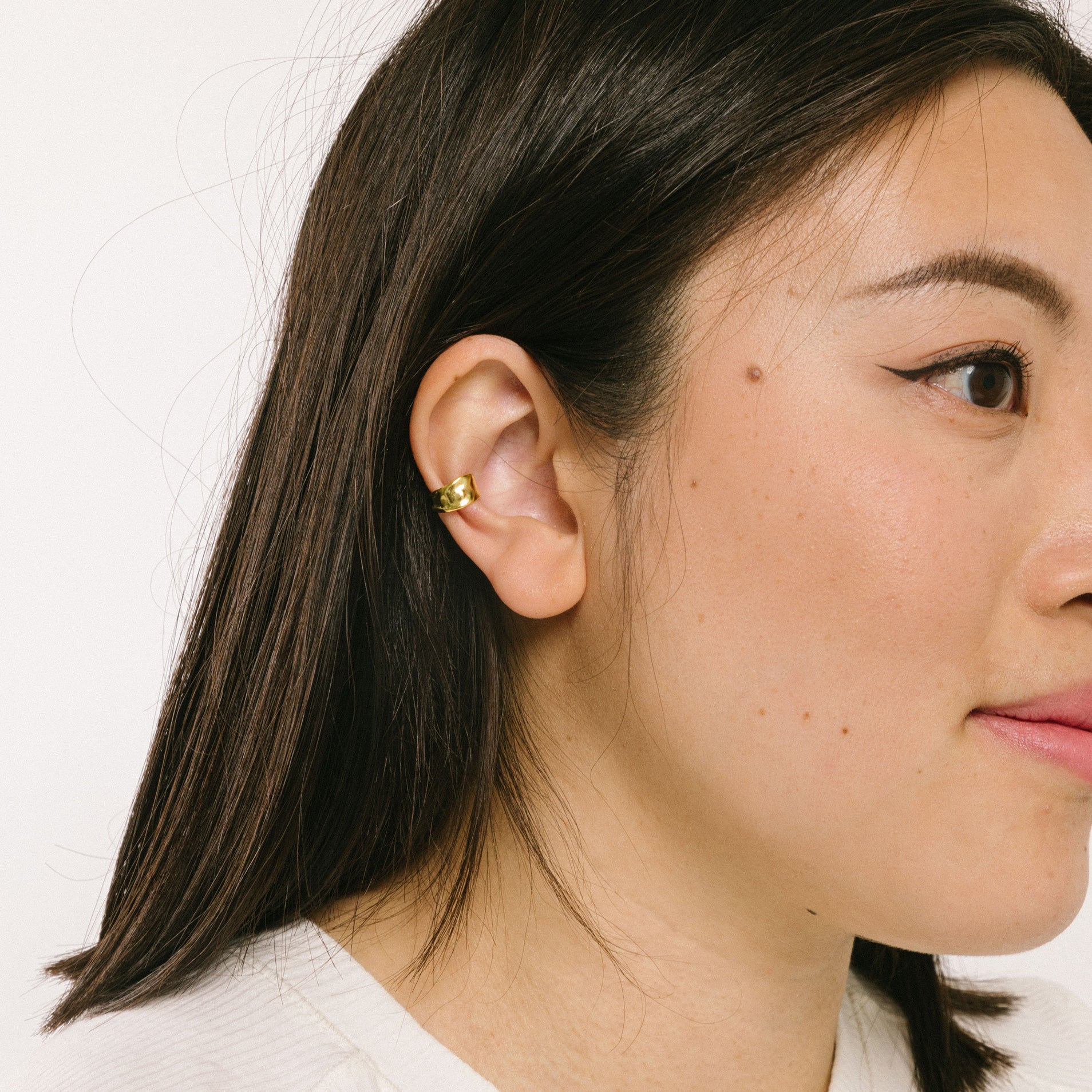 A model wearing the Aya Ear Cuff in Gold, made with 925 Sterling Silver for a timeless, luxurious style. Slip on these classy clip-on earrings to instantly elevate your look.