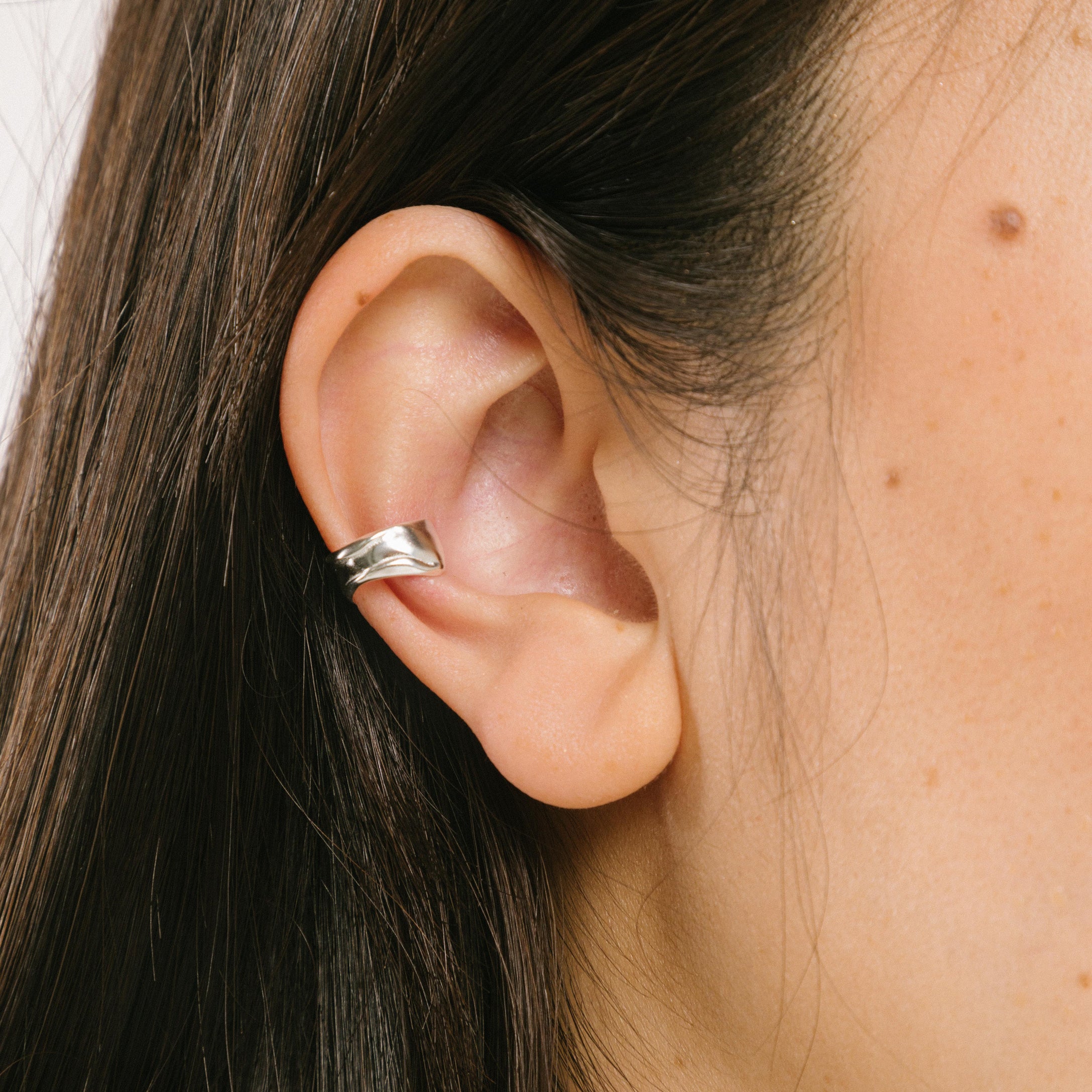 A model wearing the Aya Ear Cuff in Silver, made with 925 Sterling Silver for a timeless, luxurious style. Slip on these classy clip-on earrings to instantly elevate your look.