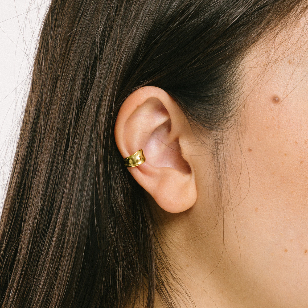 A model wearing the Aya Ear Cuff in Gold, made with 925 Sterling Silver for a timeless, luxurious style. Slip on these classy clip-on earrings to instantly elevate your look.