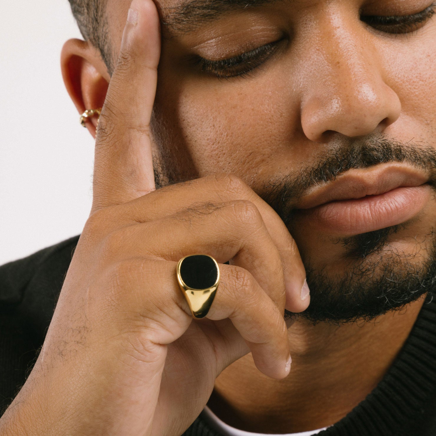 A model wearing the Black Signet Ring is crafted with 18K Gold Plating, which is resistant to tarnishing and water damage.