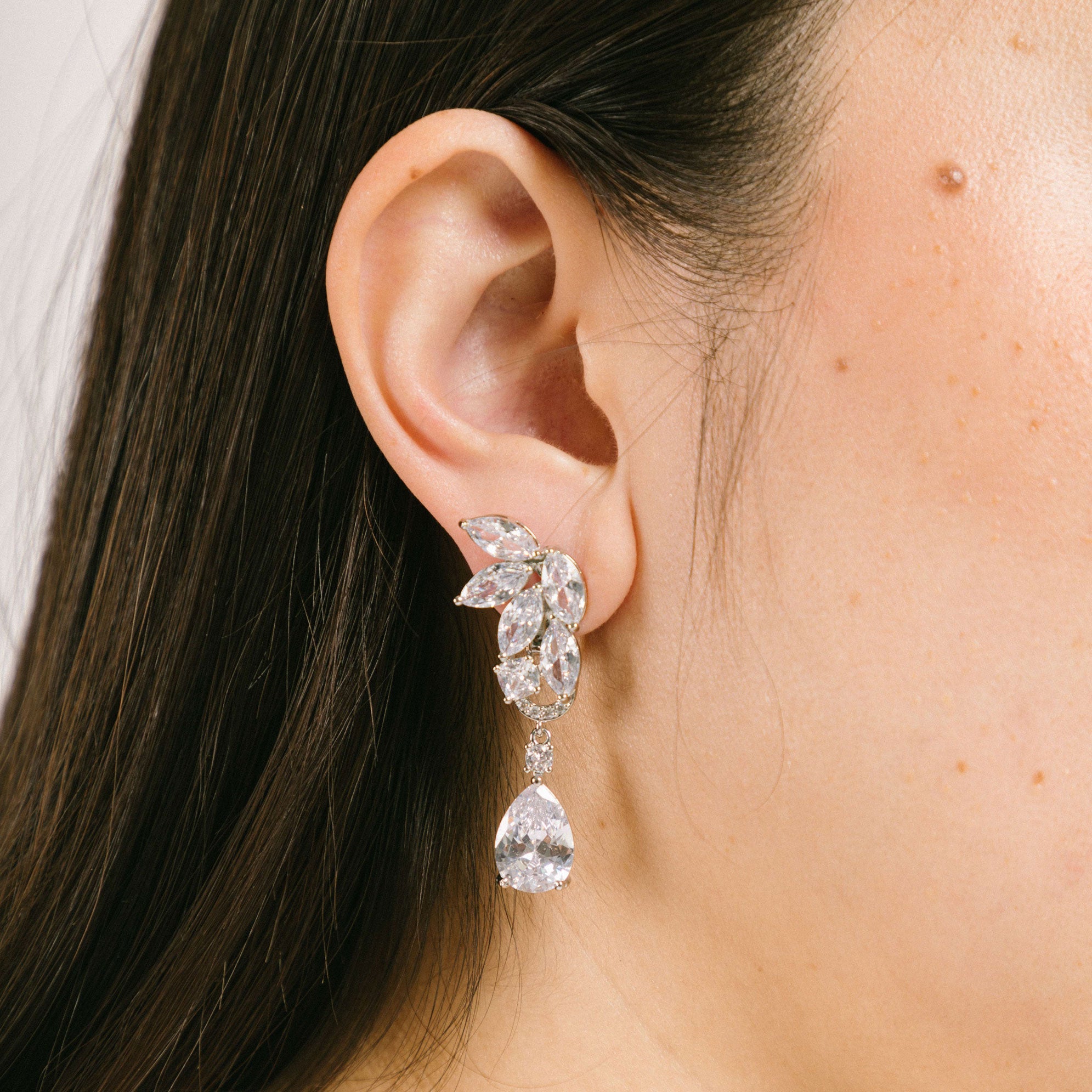 A model wearing the Layla Clip-On Earrings boast a secure and comfortable hold that can last up to 12 hours. Features include a padding clip-on closure, making it suitable for all ear types including thick, sensitive, thin, and stretched ears. Made from a silver plated, copper alloy and free of lead, nickel, and cadmium, this single pair of earrings is perfect for long-lasting wear. The removable rubber padding further promises an adjustable, comfortable fit.
