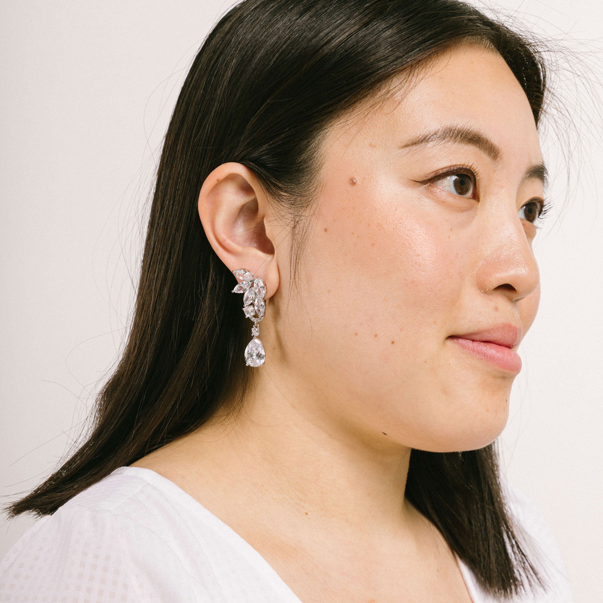 A model wearing the Layla Clip-On Earrings boast a secure and comfortable hold that can last up to 12 hours. Features include a padding clip-on closure, making it suitable for all ear types including thick, sensitive, thin, and stretched ears. Made from a silver plated, copper alloy and free of lead, nickel, and cadmium, this single pair of earrings is perfect for long-lasting wear. The removable rubber padding further promises an adjustable, comfortable fit.