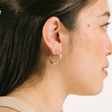 A model wearing the Silver Cassie Hoop Clip-On Earrings have a resin clip-on closure type and are suitable for all ear types, from thick/large ears to small/thin ears and stretched/healing ears. On average, comfortably wear for 8-12 hours, with a medium secure hold. Unfortunately, these earrings are unable to be adjusted. Offered in Silver Tone metal alloy, the earrings also come in Gold.