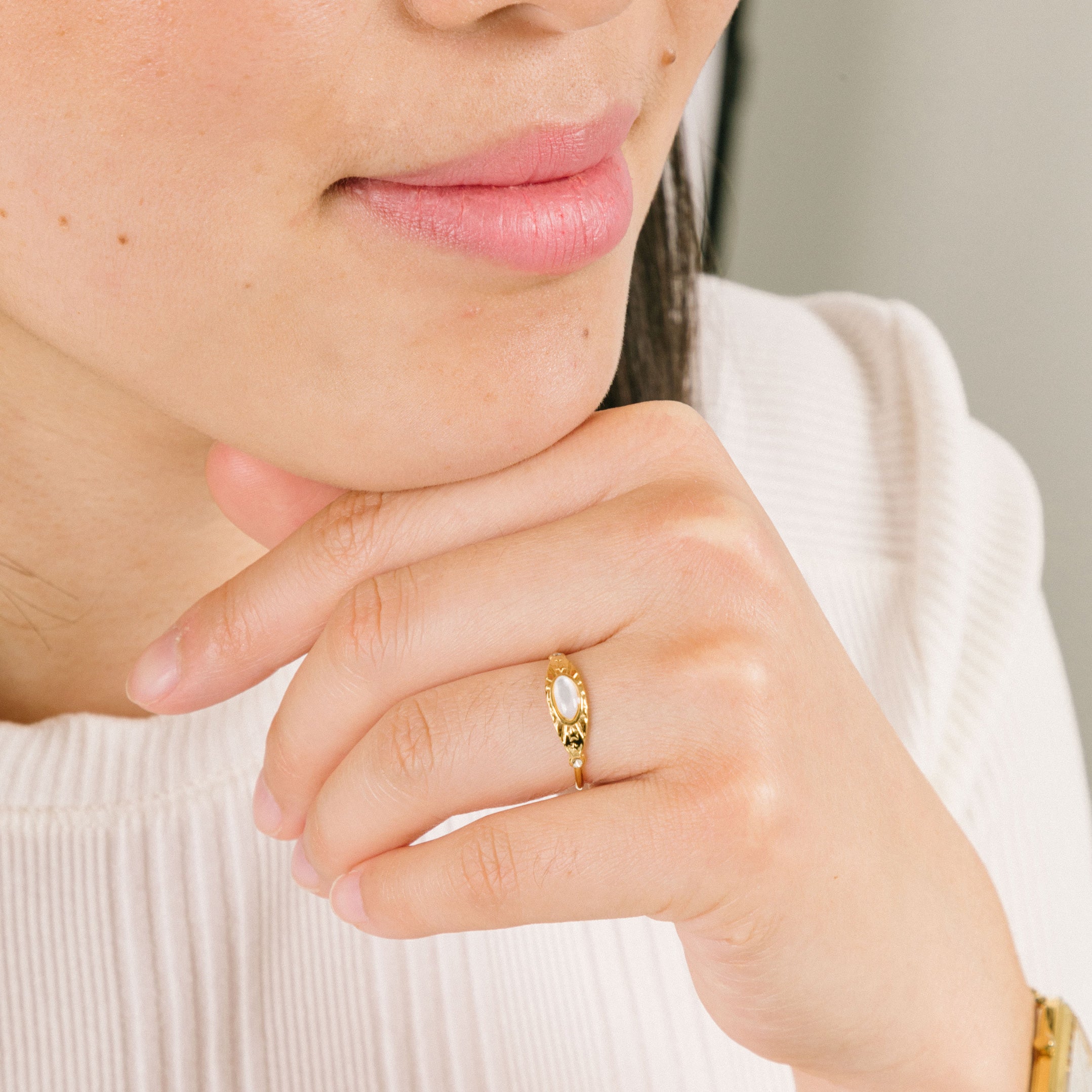 A model wearing the Celestial Ring, adorned with a luminous Mother of Pearl centerpiece and 18K Gold Plated Stainless Steel. A singularly exquisite piece, sure to never fade nor tarnish, and resilient to water.