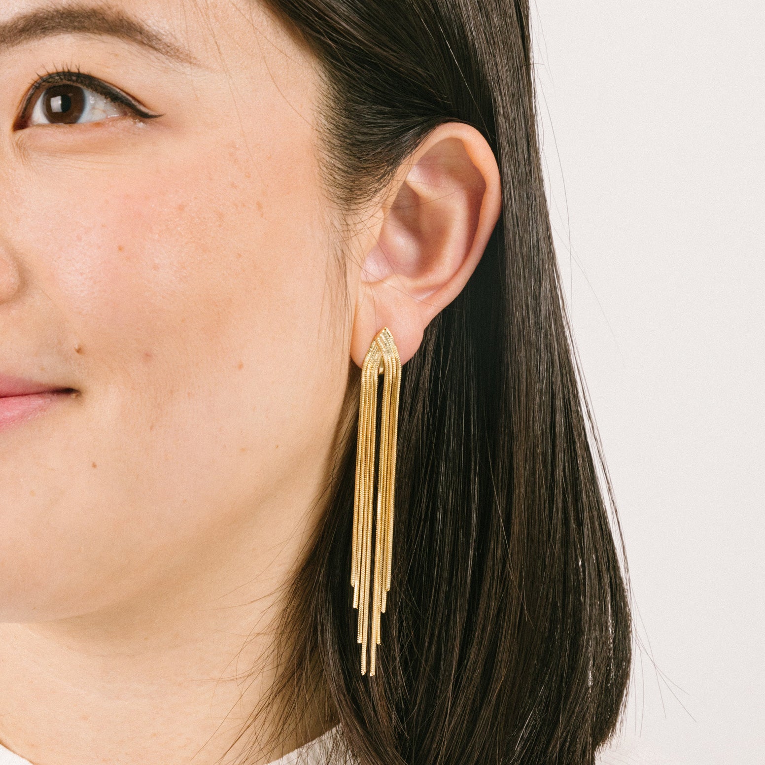 A model wearing the Chain Chandelier Clip On Earrings in Gold embody a removable rubber padding for secure yet comfortable holding of all ear types, with up to 12 hours of wear. This single pair, fashioned from gold tone copper alloy, offers an immediate air of refinement and distinction.