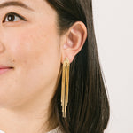 A model wearing the Chain Chandelier Clip On Earrings in Gold embody a removable rubber padding for secure yet comfortable holding of all ear types, with up to 12 hours of wear. This single pair, fashioned from gold tone copper alloy, offers an immediate air of refinement and distinction.