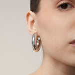 A model wearing the Chunky Hoop Clip On Earrings in Silver. With a secure screwback closure, these earrings are suitable for a variety of ear sizes, including sensitive and keloid-prone ears. Designed for long-lasting wear and can be manually adjusted for a perfect fit. Note: includes one pair.
