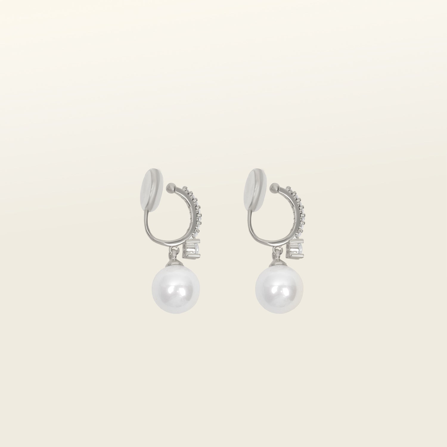 Image of the Claire Pearl Clip On Earrings in Silver present a mosquito coil clip-on closure crafted to accommodate all ear types—from thick/large to sensitive, from small/thin to stretched/healing—ensuring a comfortable fit. Intricately constructed from silver tone copper alloy, Cubic Zirconia, and Simulated Faux Pearl, these earrings add a sophisticated touch to any ensemble.