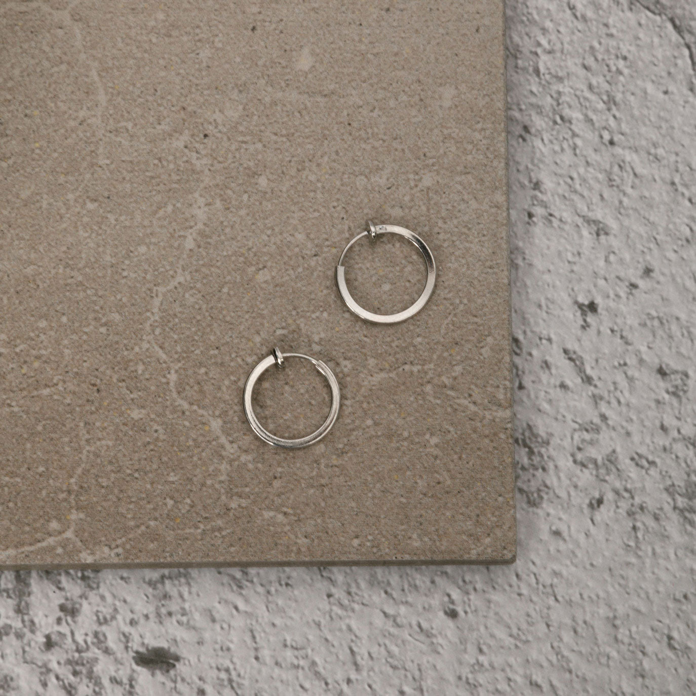 Image of the Classic Hoop Clip On Earrings feature a sliding spring closure that is ideal for small or thin ear lobes. The secure hold enables comfortable wear up to 4 hours, and the design automatically adjusts to the thickness of the ear. Crafted from stainless steel, the earrings come as a single pair.