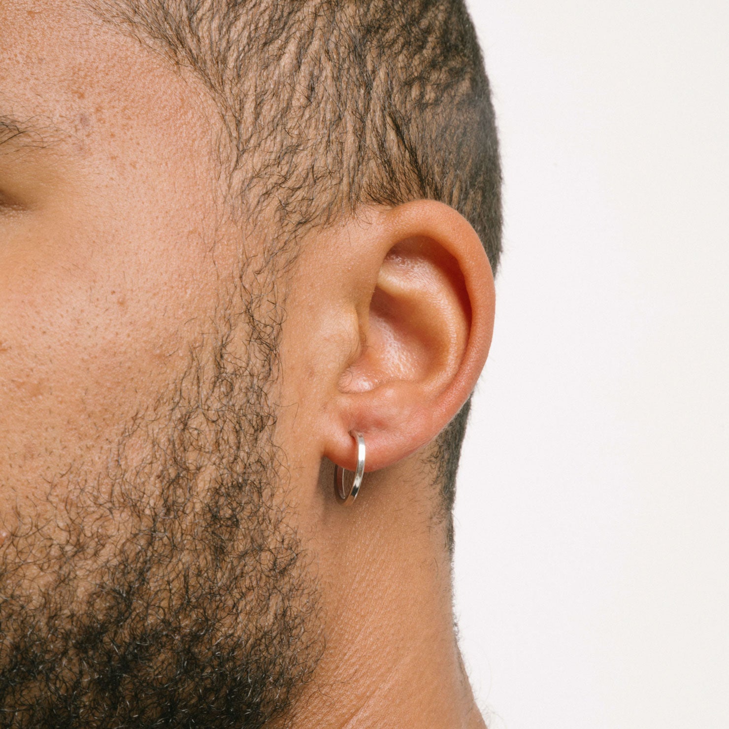 A model wearing the Classic Hoop Clip On Earrings feature a sliding spring closure that is ideal for small or thin ear lobes. The secure hold enables comfortable wear up to 4 hours, and the design automatically adjusts to the thickness of the ear. Crafted from stainless steel, the earrings come as a single pair.