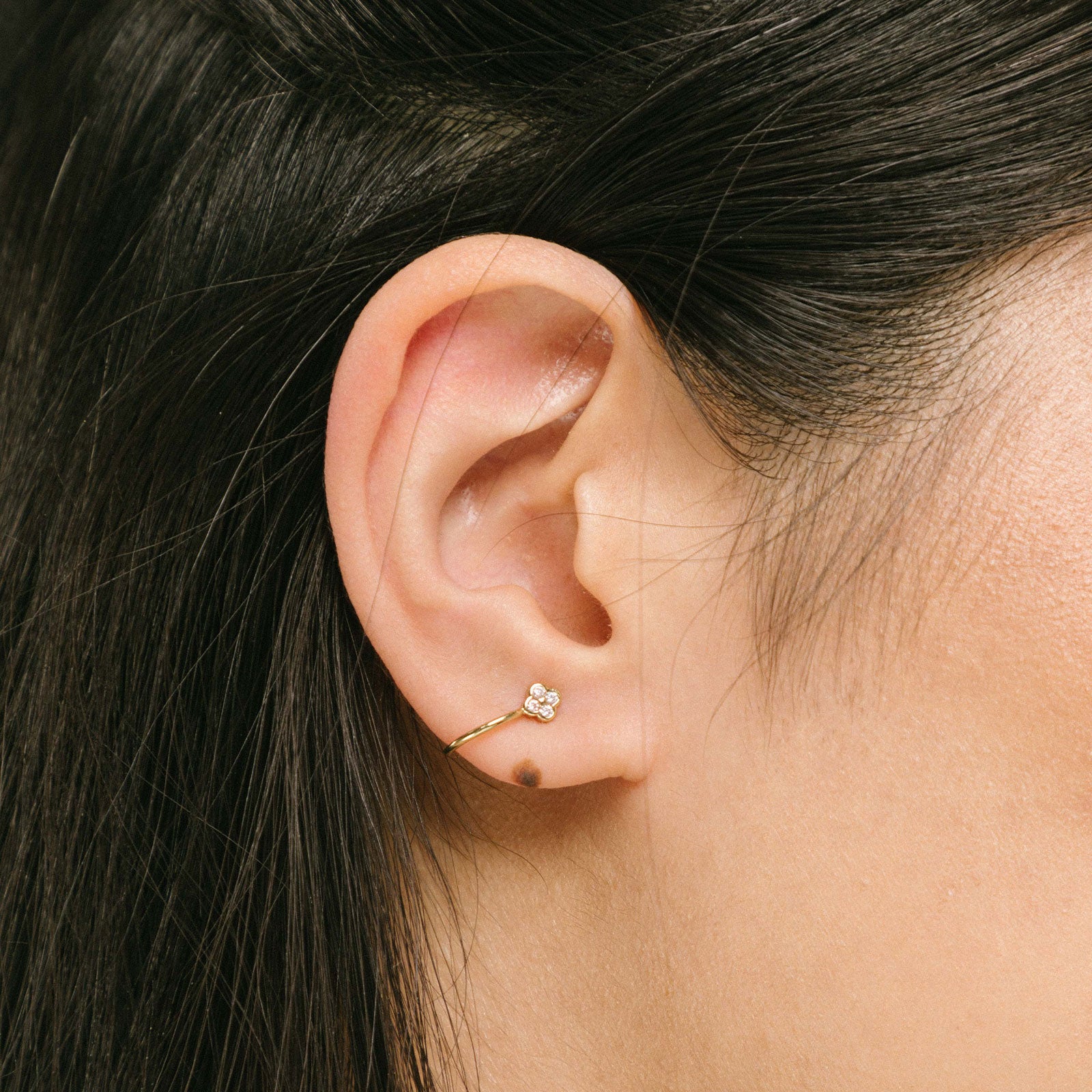 A model wearing our Gold Clover Ear Cuff, a chic and versatile accessory. Made from Gold or Silver Plated Copper alloy, this modern clover-shaped ear cuff features 4 sparkling Cubic Zirconia stones. Ideal for both the nose and ear, it effortlessly adds sophistication to any outfit, allowing you to adorn yourself with style and flair.