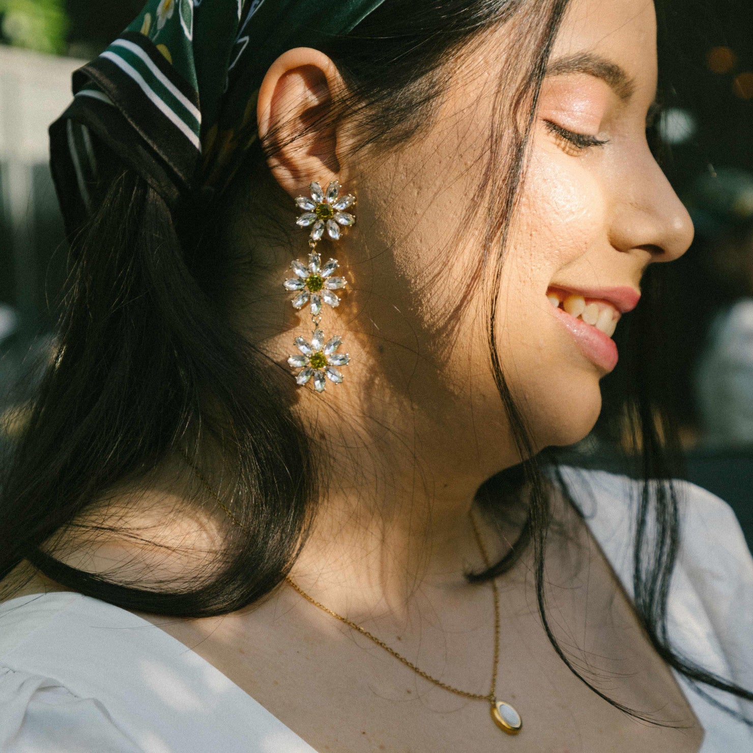 A model wearing the Crystal Flower Drop Clip On Earrings feature a Padded Clip-On closure, perfect for ears of larger proportions as the earrings are on the heavier side. Constructed of gold tone copper alloy and Rhinestone, with detachable rubber padding for added comfort, these earrings provide up to 8-12 hours of easy wear. Sold as one single pair.