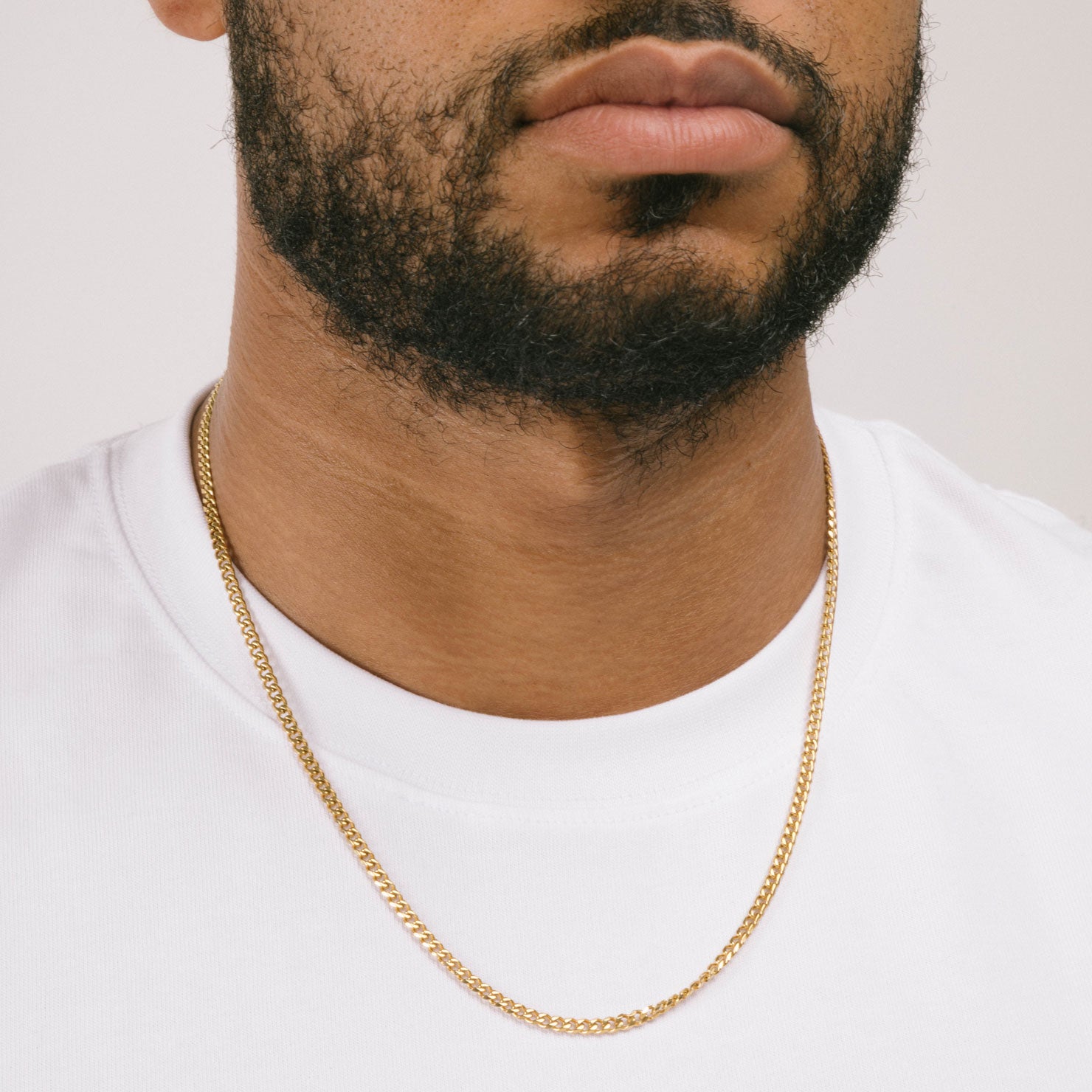 A model wearing the Cuban Chain in Gold is crafted from 18K Gold Plated material and is non-tarnish, water-resistant, and designed to be hypoallergenic.