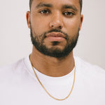 A model wearing the Cuban Chain in Gold is crafted from 18K Gold Plated material and is non-tarnish, water-resistant, and designed to be hypoallergenic.