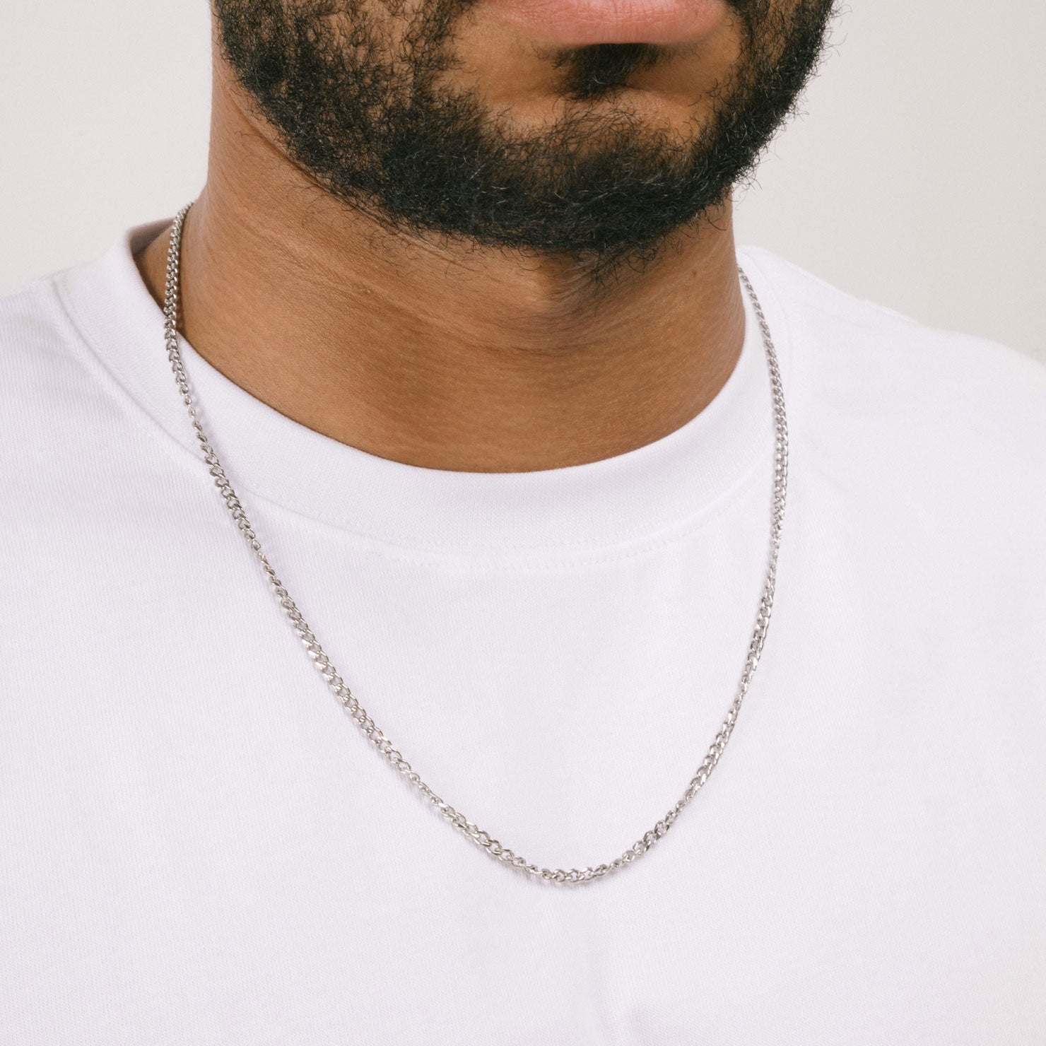 A model wearing the Cuban Chain in Silver is crafted from Stainless Steel material and is non-tarnish, water-resistant, and designed to be hypoallergenic.