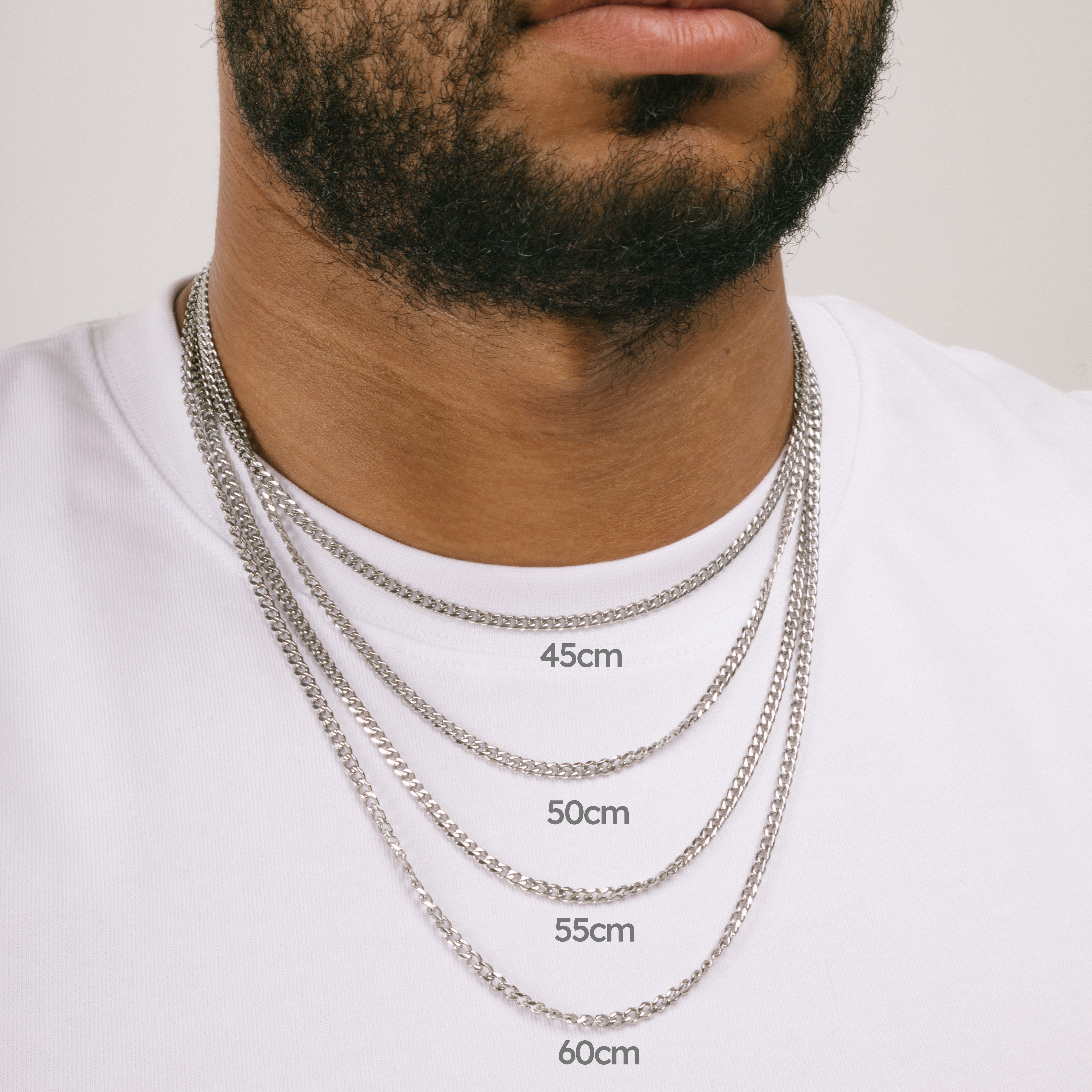    A model wearing the Cuban Chain in Silver is crafted from Stainless Steel material and is non-tarnish, water-resistant, and designed to be hypoallergenic.