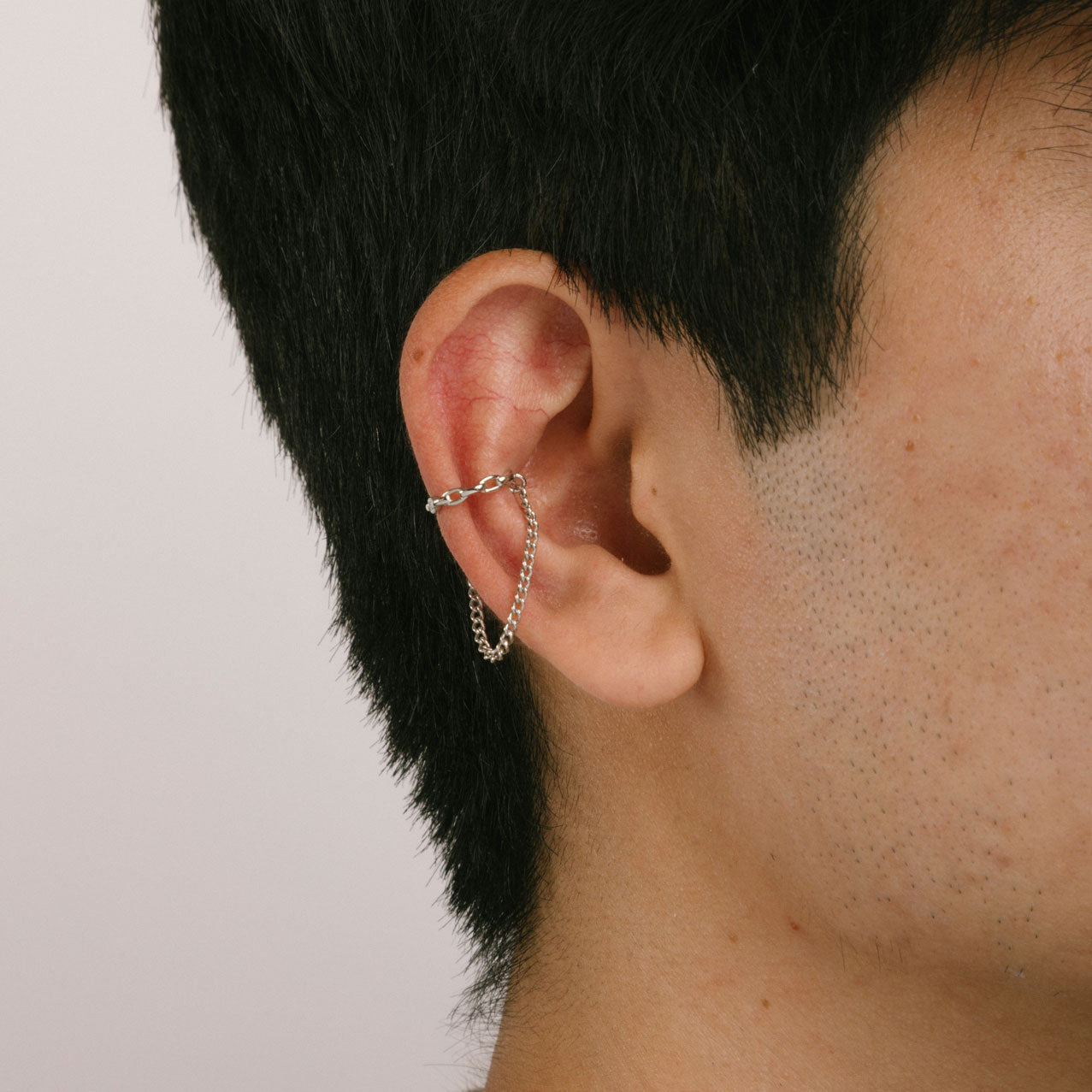 A model wearing the Silver Double Chain Ear Cuff is designed for a comfortable and secure fit on all ear types. You can easily adjust it to your desired level of hold strength, and it will stay in place for up to 24 hours. The cuff is crafted from a silvertone plated zinc alloy material. Please note that the item is sold as a single piece.