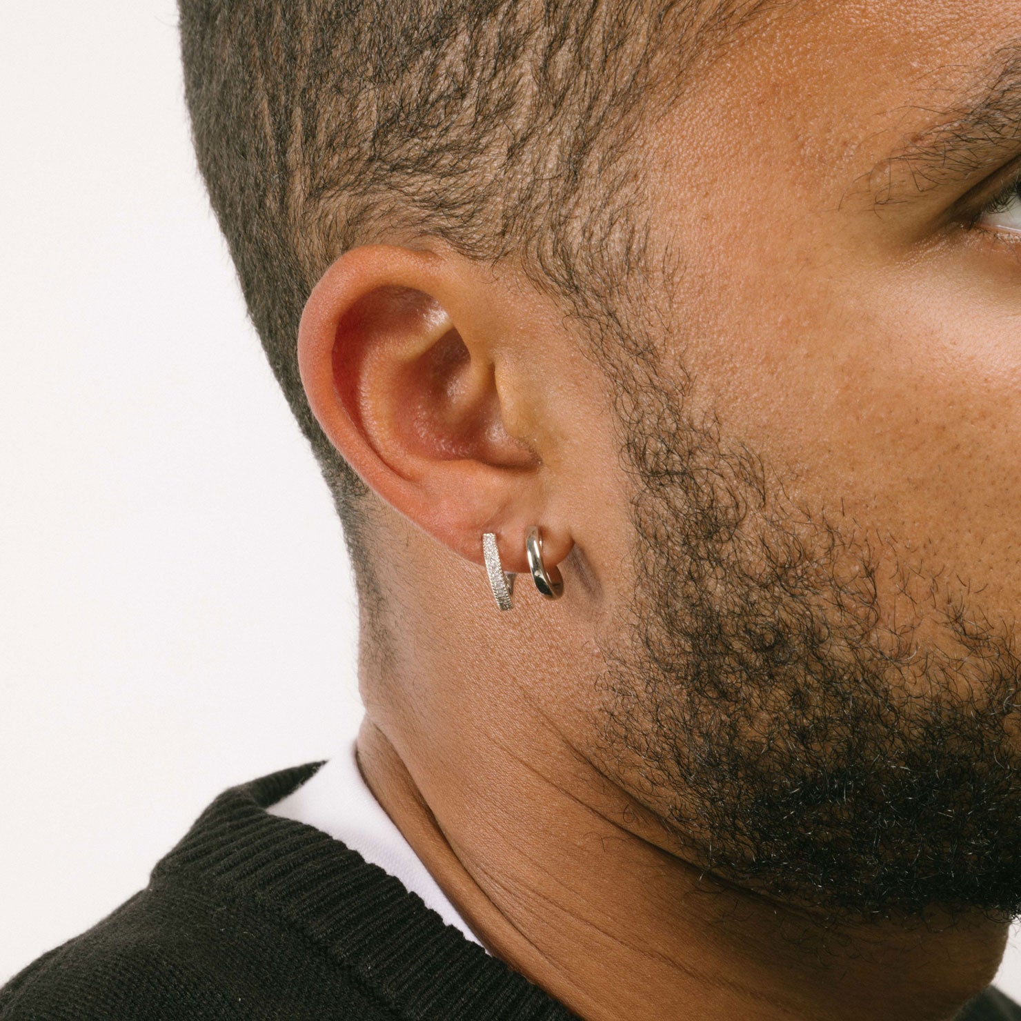 A model wearing the Double Hoop Pave Clip On Earrings in Silver feature a secure mosquito coil clip-on closure for most ear types. With an easy adjustable design, these earrings can be worn for 24 hours with a comfortable medium hold. Made of sterling silver plated copper with a Cubic Zirconia detail, these earrings are a great addition to any wardrobe.