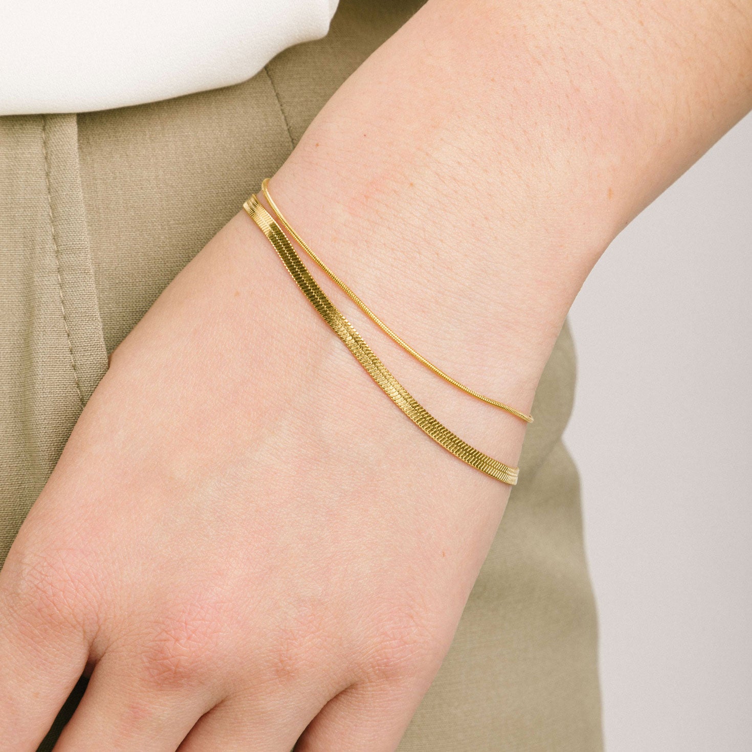 A model wearing the Double Layered Bracelet is crafted from 14K gold plated stainless steel for outstanding durability and a non-tarnish, water-resistant, allergy-free and antioxidant finish. Plus, its adjustable design ensures a perfect fit for any wrist.