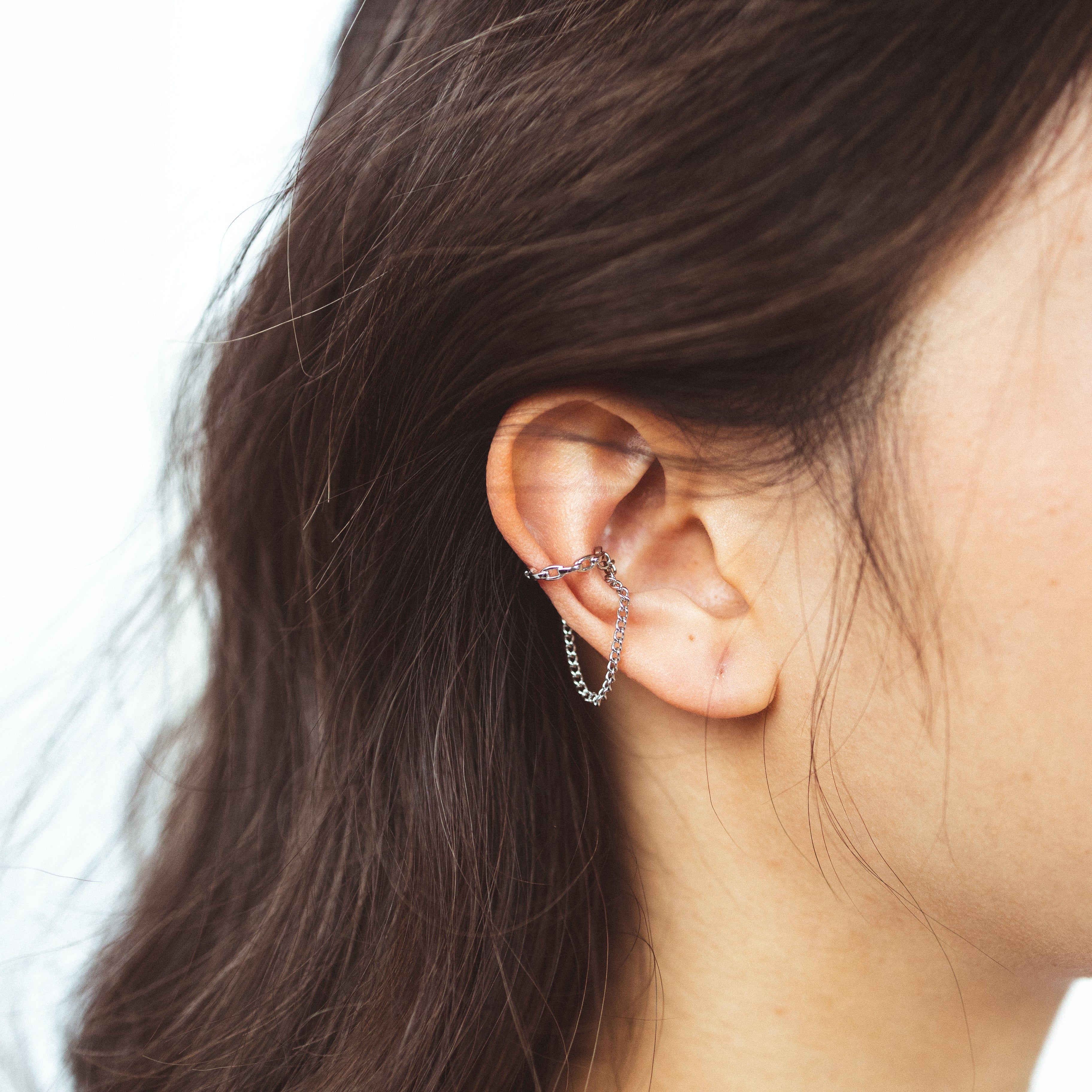Model Image of a modern Dual Chain Ear Cuff crafted from Goldtone or Silvertone plated zinc alloy. This trendy accessory features a delicate chain, designed to elegantly adorn the earlobe of both men and women.
