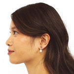 A model wearing the Elio Clip On Earrings. Designed for all ear types, these elegant earrings provide a secure hold for up to 24 hours. Enjoy unparalleled comfort and style, perfect for those with sensitive or stretched ears. Upgrade your style effortlessly with Elio.